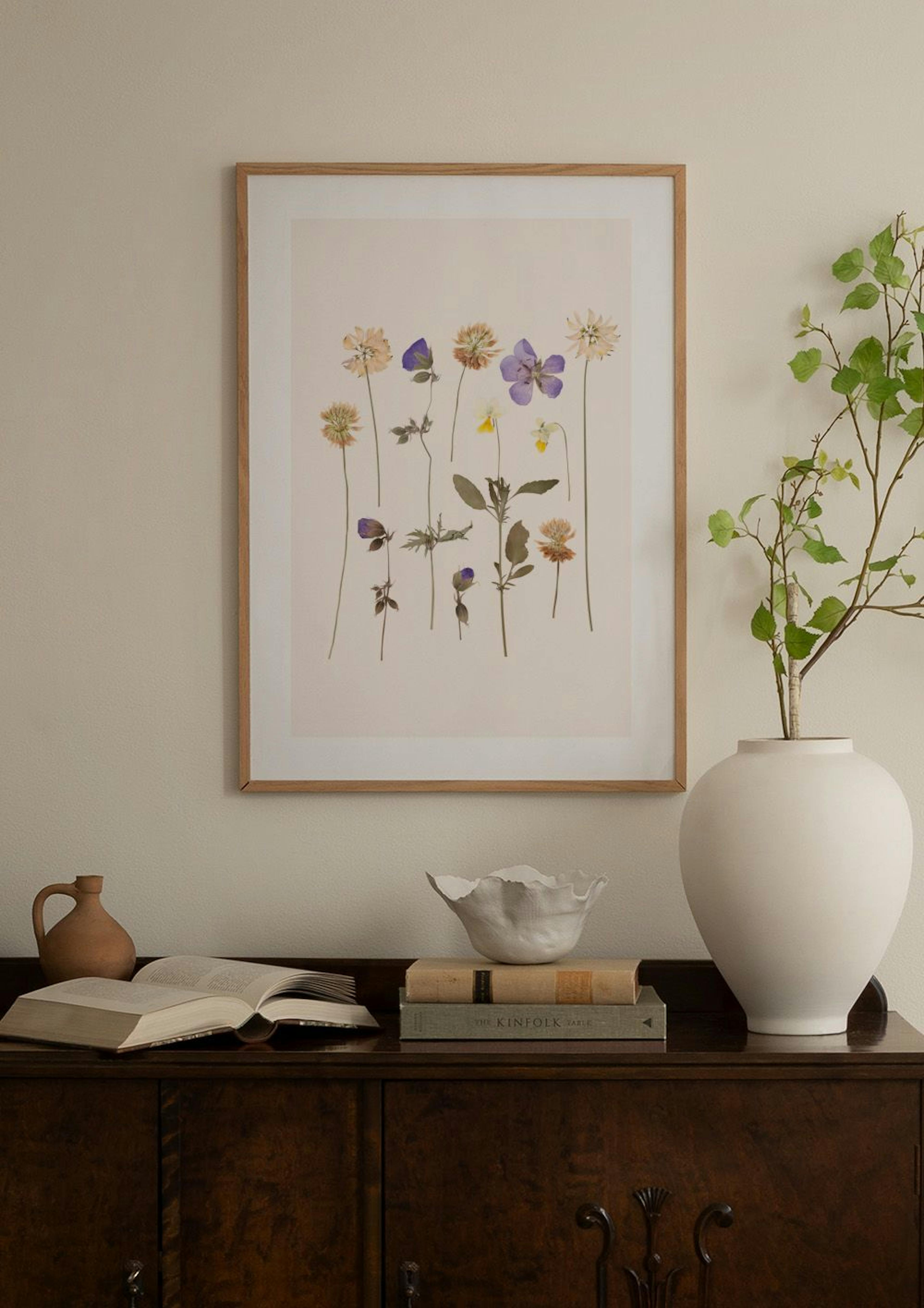 Poster met gedroogde bloemen in diverse kleuren, zwevend boven een wit dressoir met vazen.