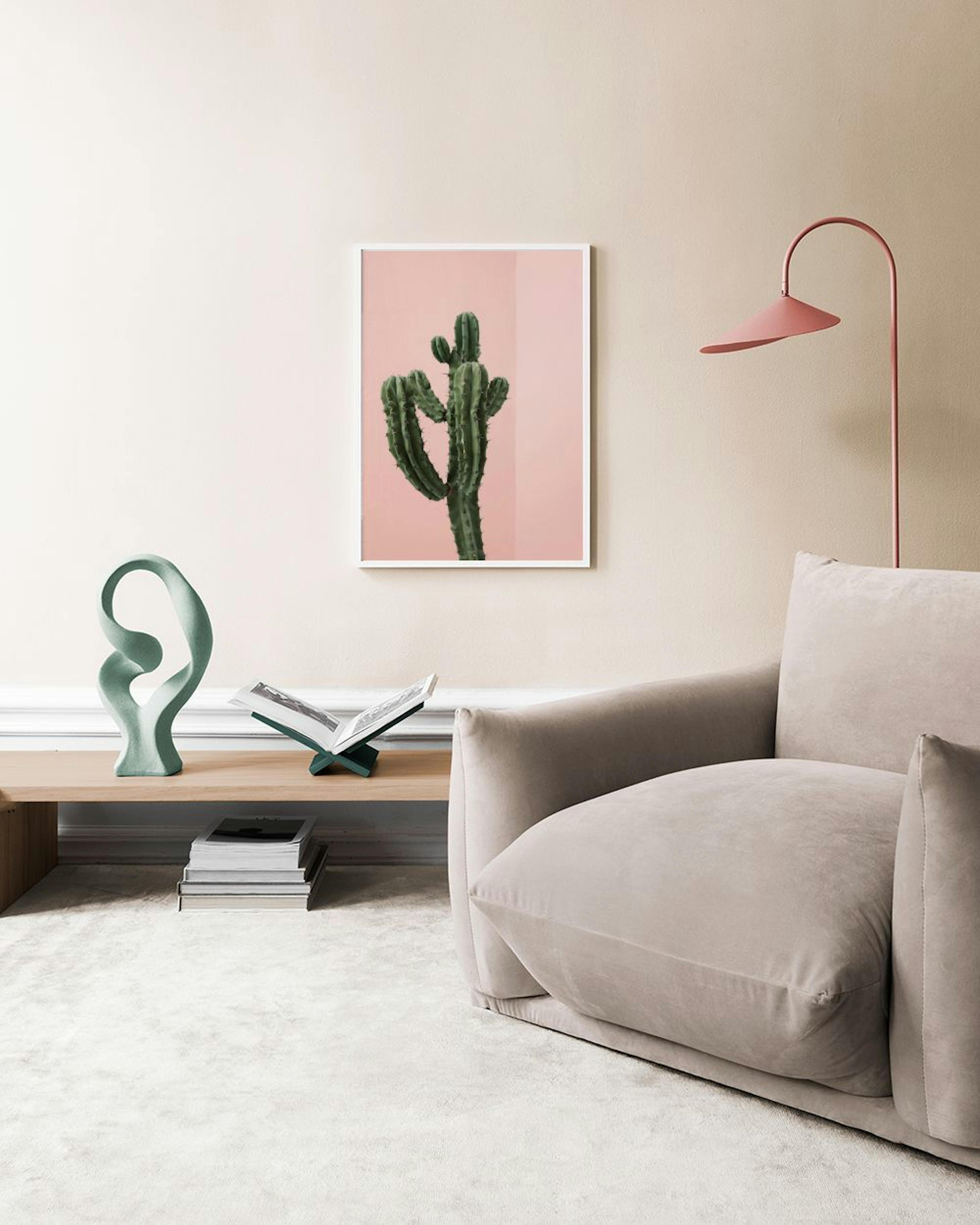 A cactus print with a light pink background, displayed above a pink velvet daybed with pillows.