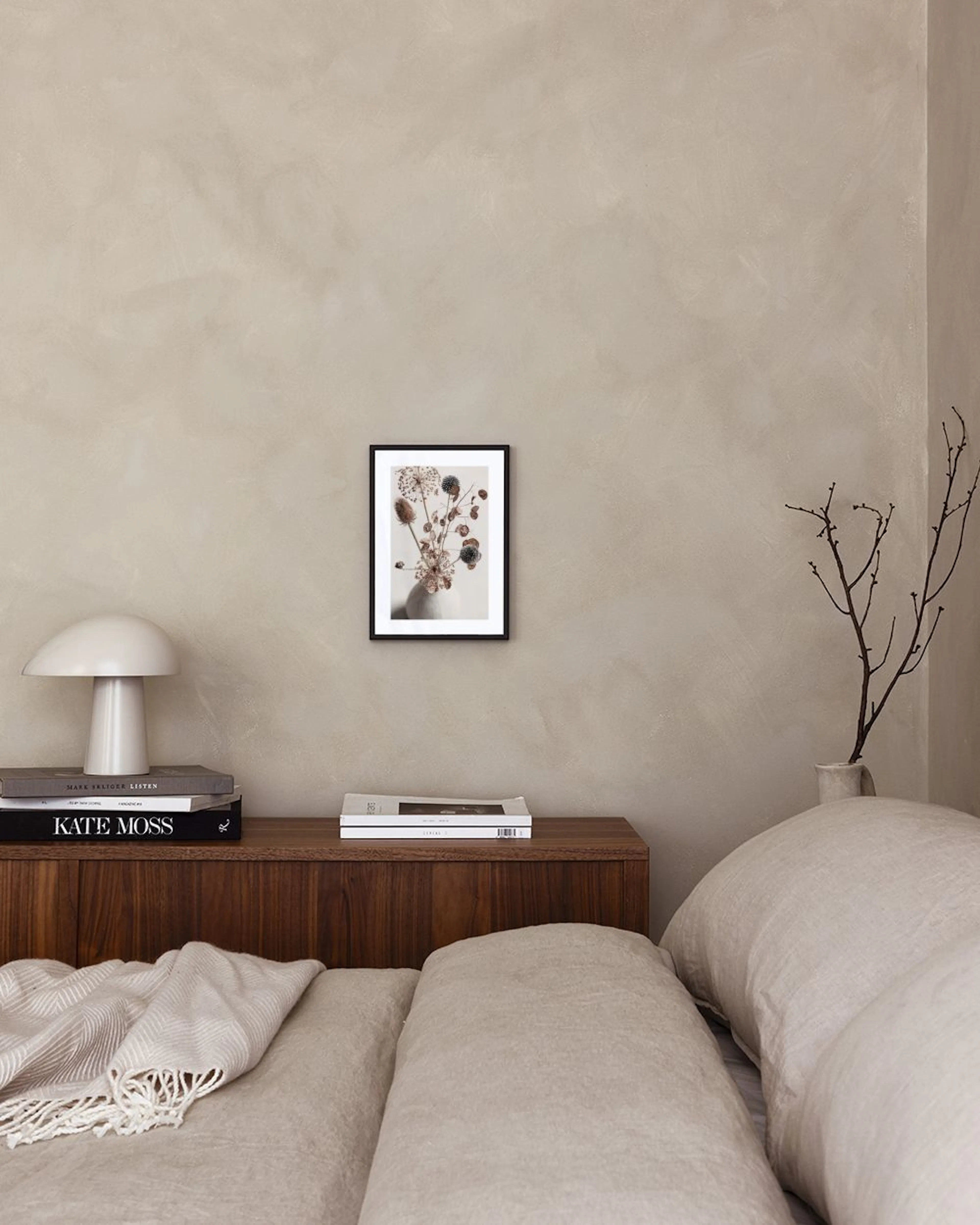 Poster van een vaas met gedroogde bloemen en zaaddozen in een minimalistische kamer met wit meubilair.