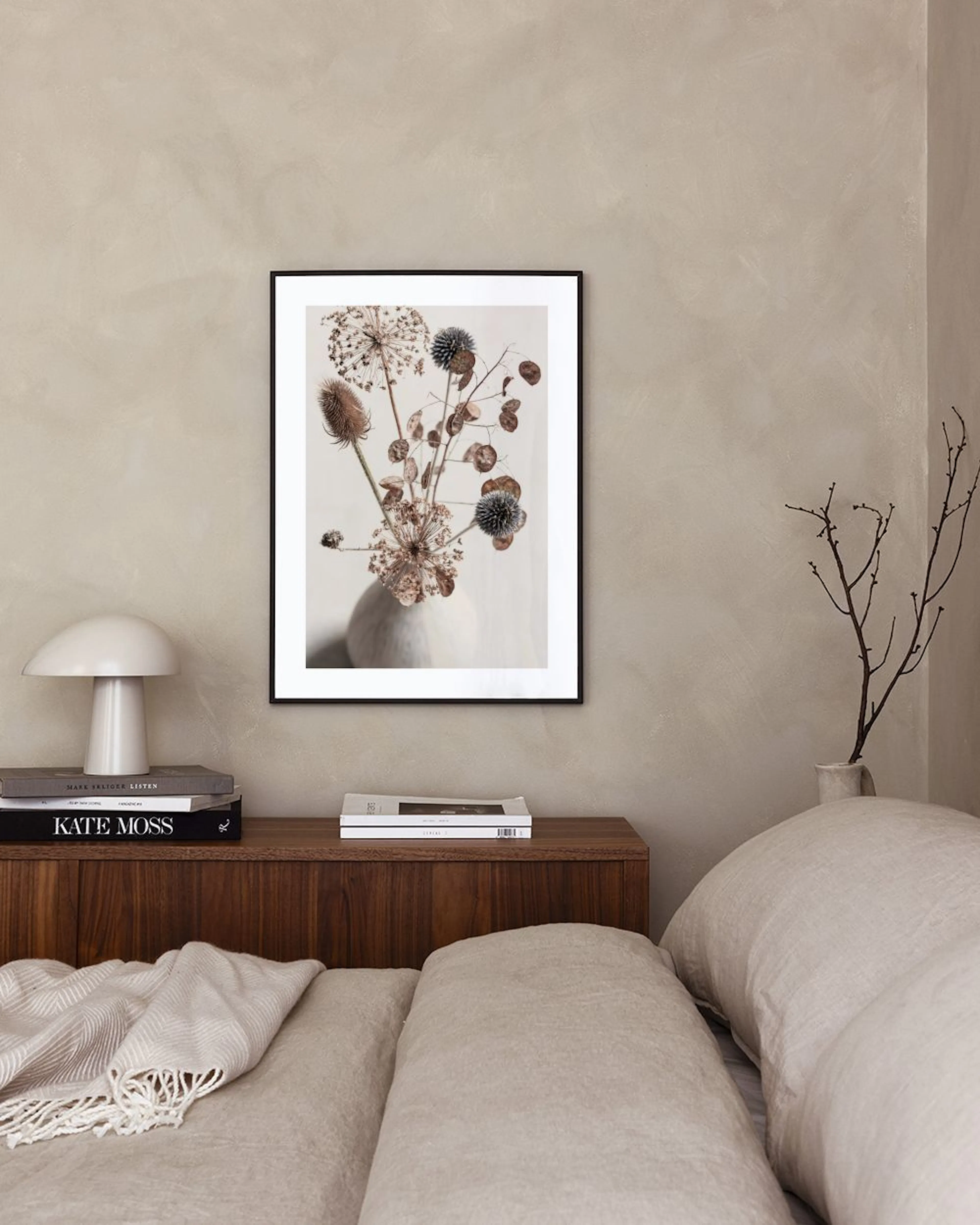 Affiche avec un bouquet de chardons et de feuilles séchées dans un vase blanc, accrochée au mur dun salon moderne.
