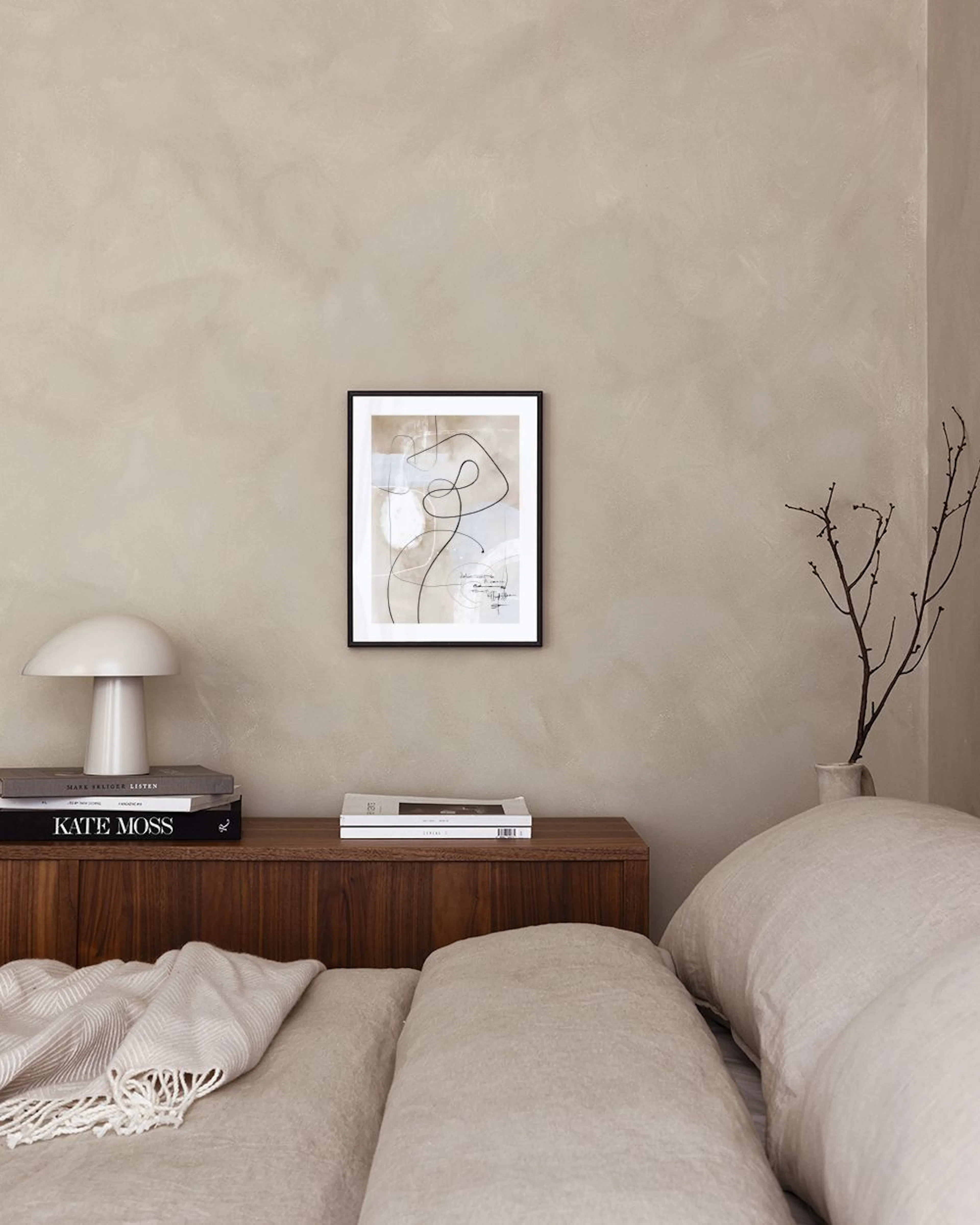 Affiche abstraite beige et grise avec des lignes noires et des formes organiques, suspendue au-dessus dun fauteuil gris à côté d
