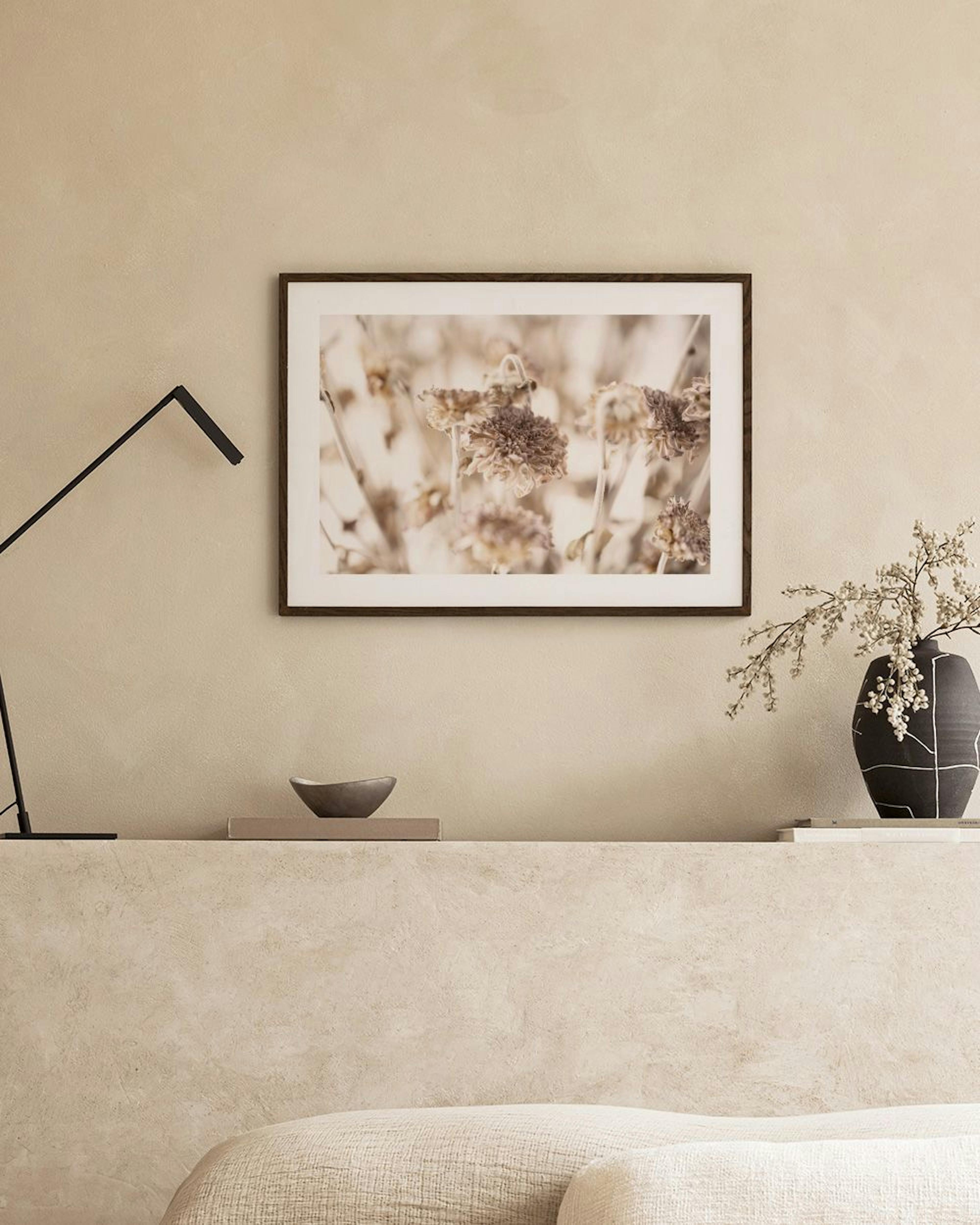 Affiche de fleurs séchées aux tons beige et marron, suspendue au-dessus dun banc en bois clair avec des livres et un vase en ter