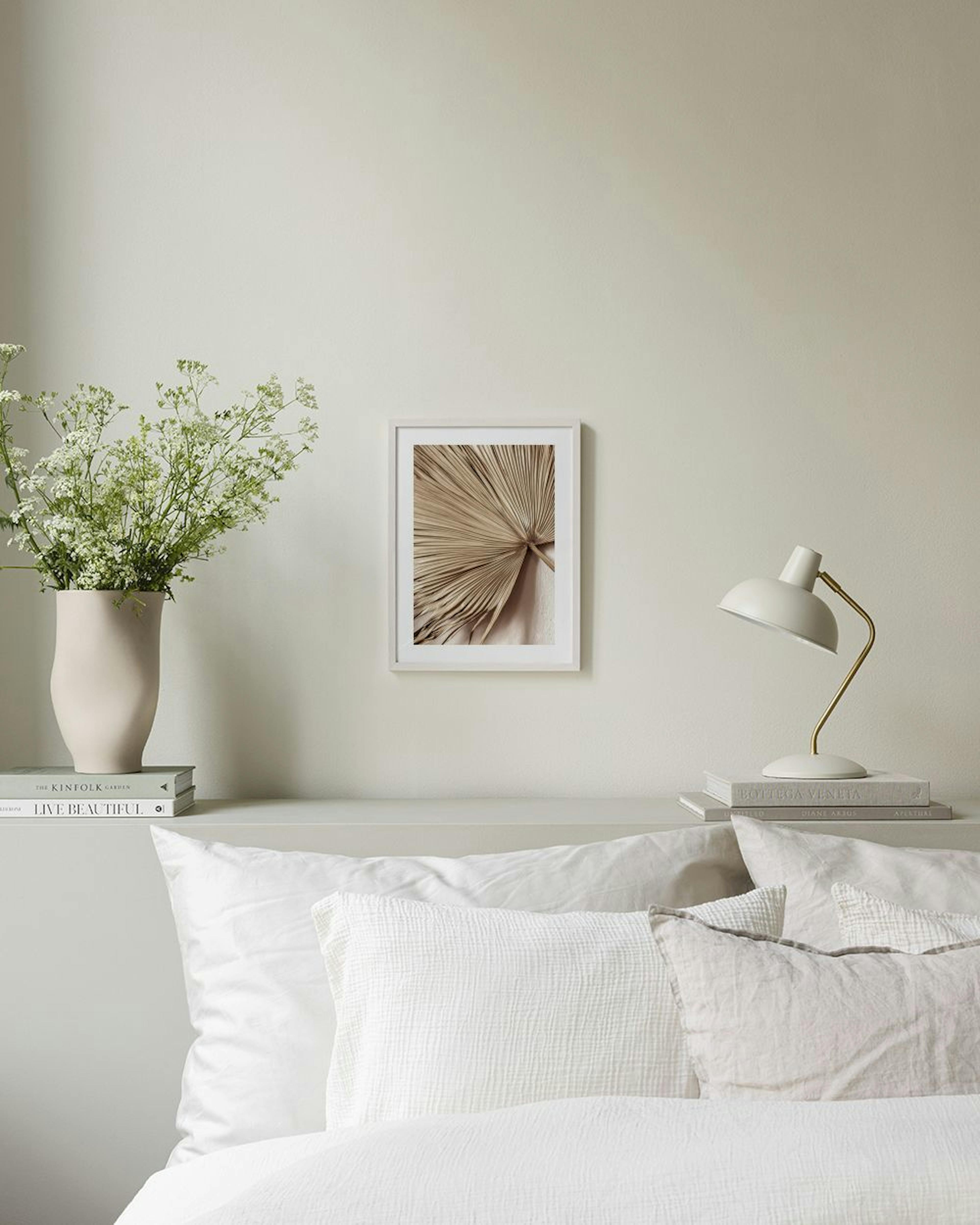 Póster de una hoja de palma seca en tonos beige y marrón, colgado en una habitación moderna sobre un puf gris.