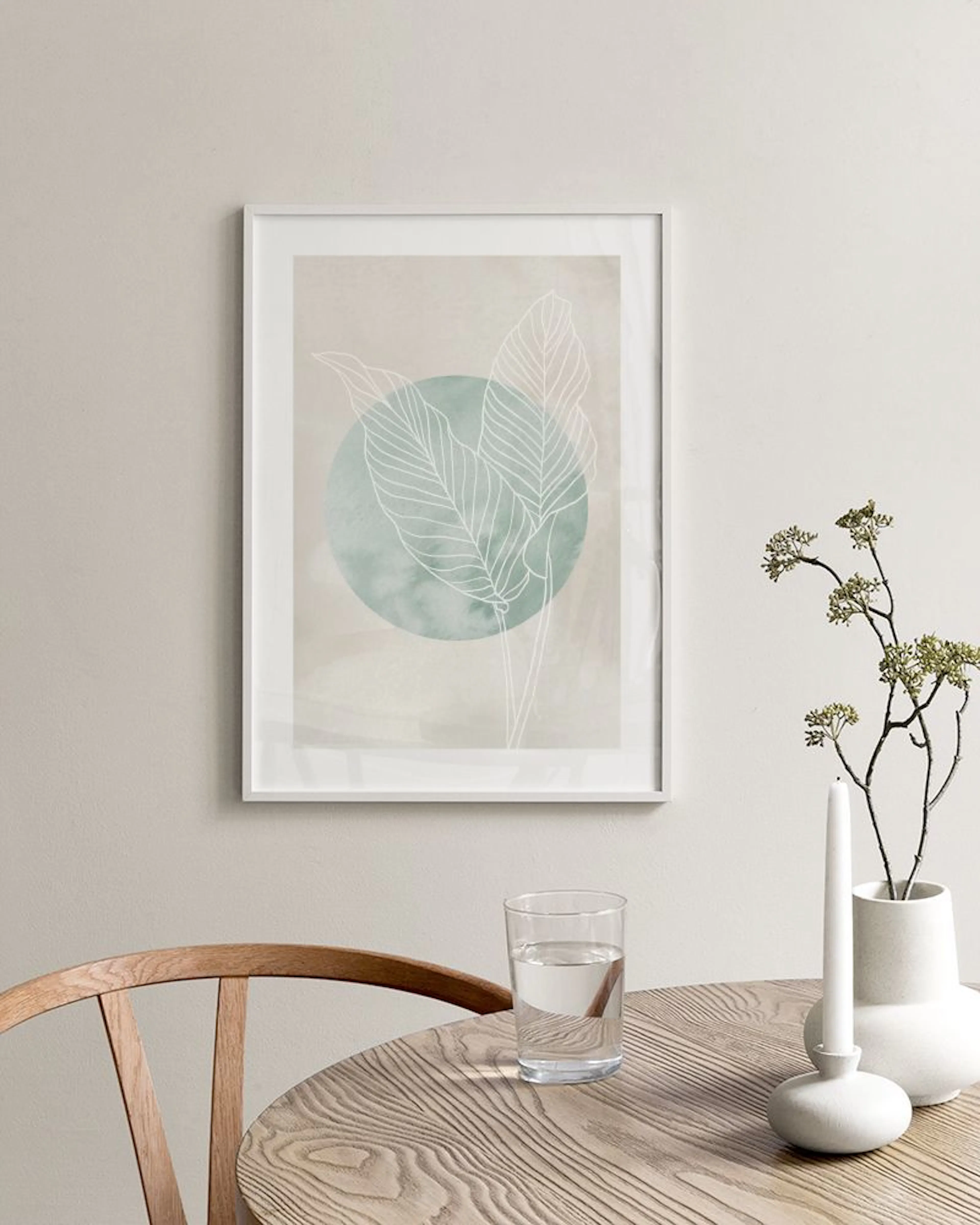 Poster con illustrazione di foglie stilizzate bianche su sfondo verde acqua e beige, appeso in una camera da letto moderna.