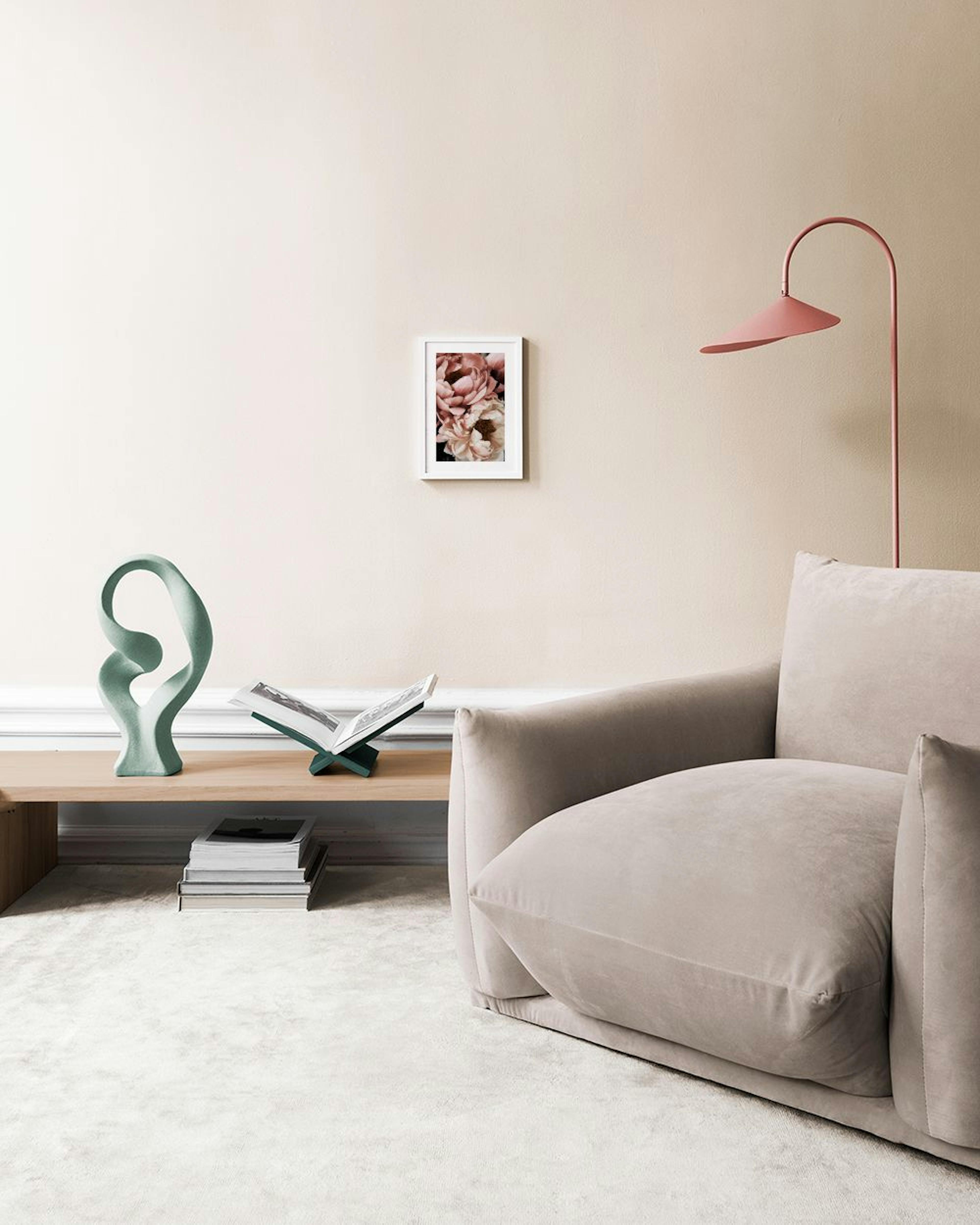 A print of two light pink peonies with dark centers, displayed above a brown cabinet with vases.