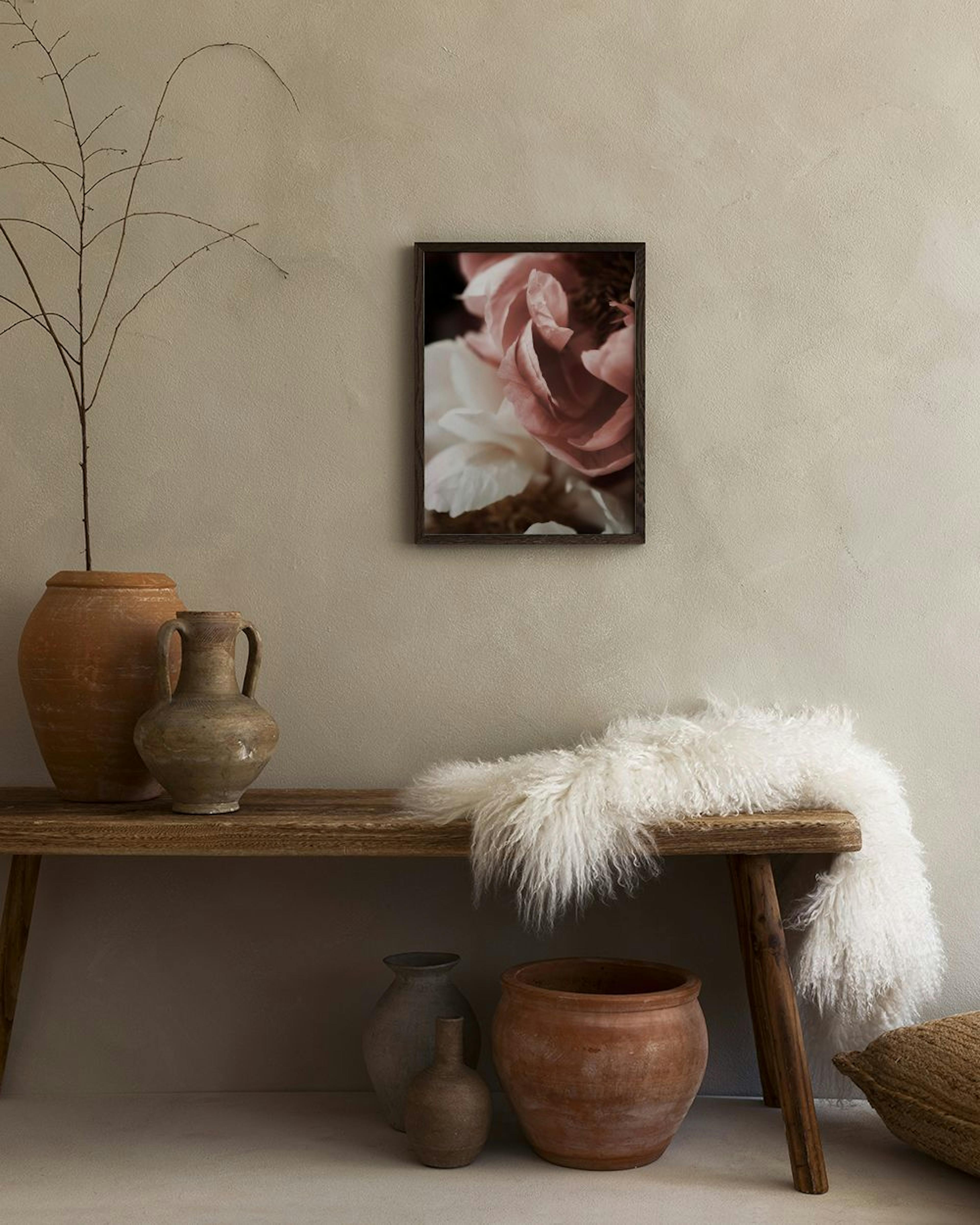 Póster de flores color rosa pálido y blanco colgado sobre un aparador moderno en tonos malva y gris.
