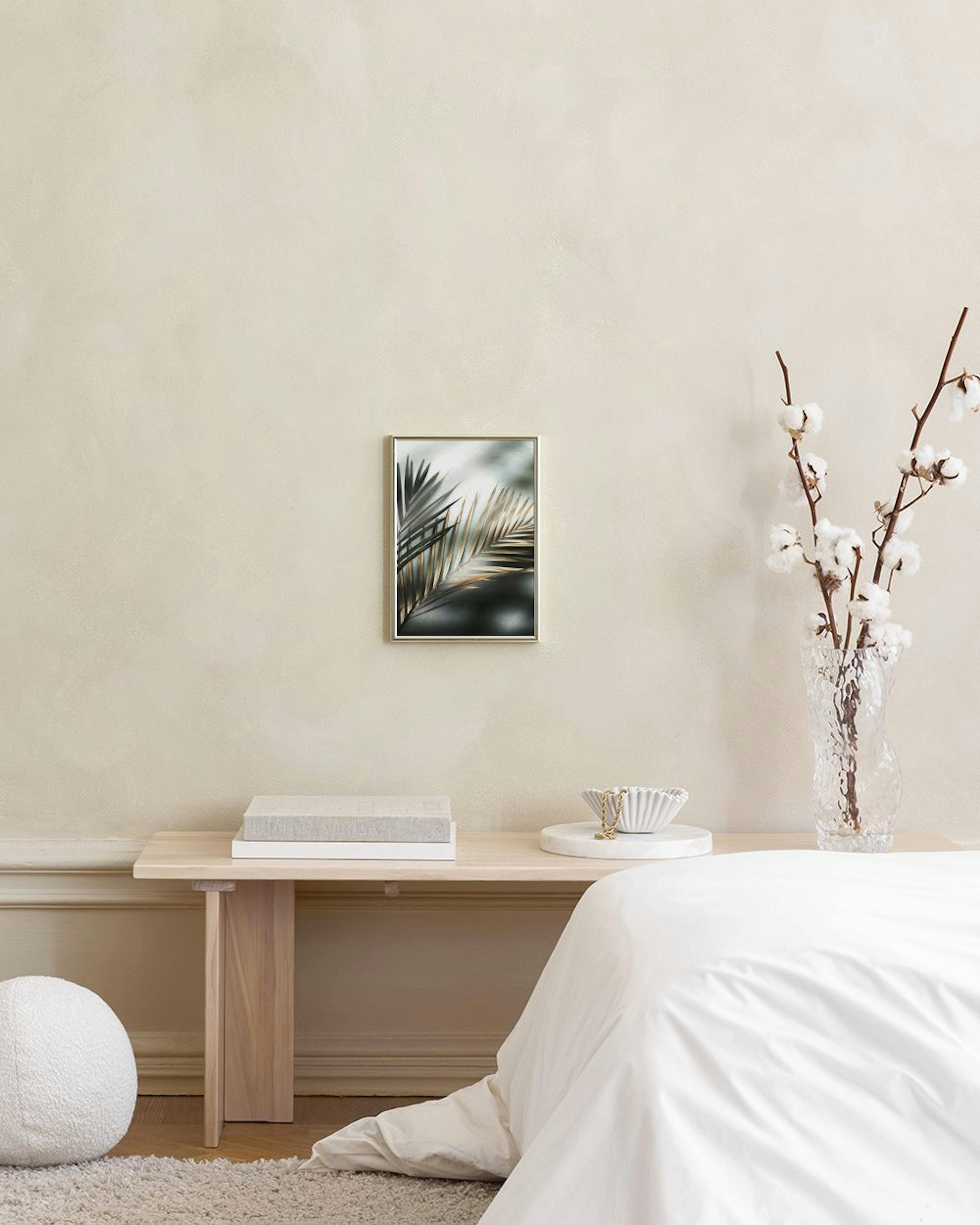 Poster mit Palmblättern in Gold- und Grautönen, an einer dunkelgrünen Wand über einem Hocker in einem eleganten Raum.