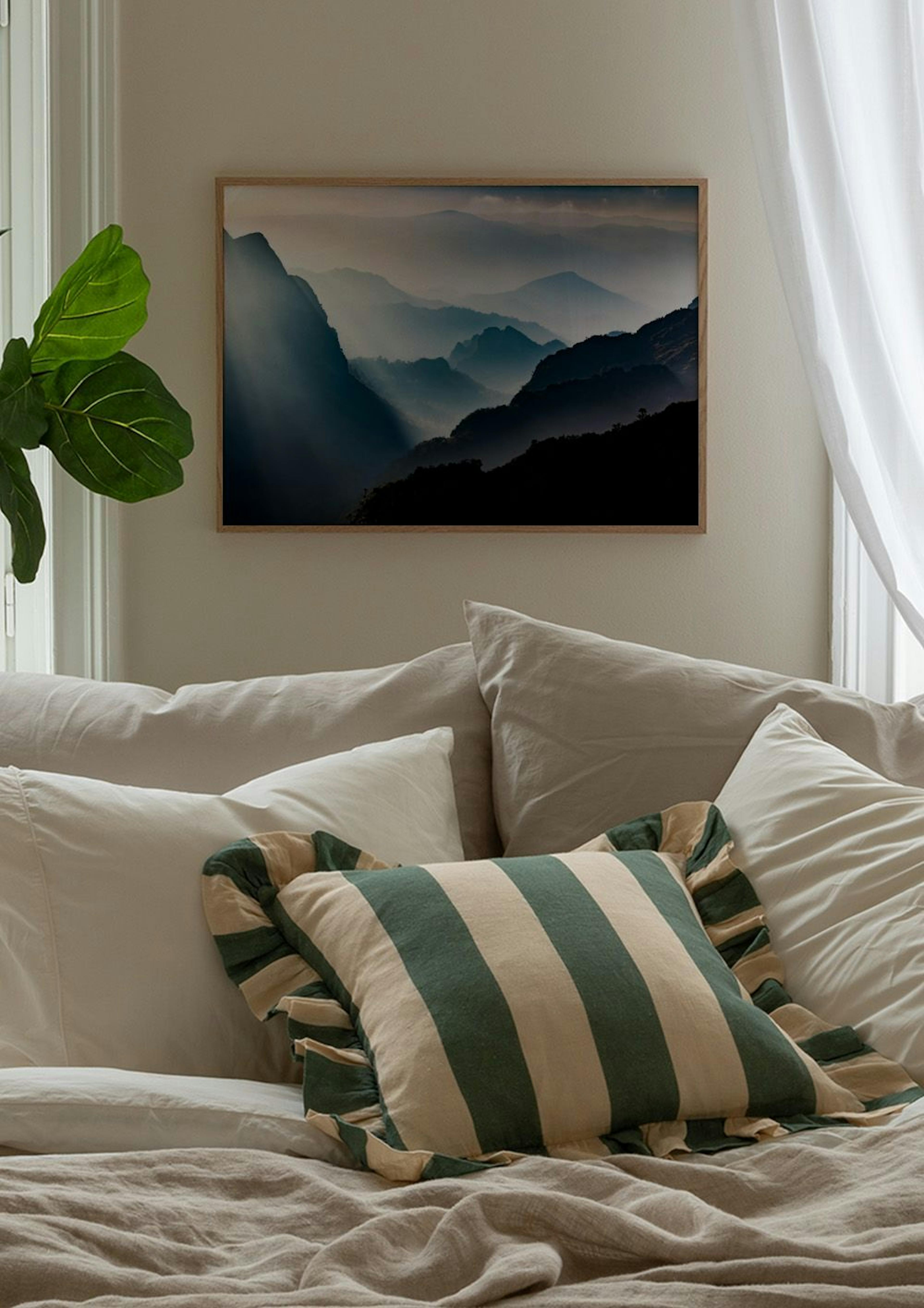 Poster van bergketens in mist gehuld, met zonnestralen doorbrekend, hangend boven een blauwe fluwelen stoel in een moderne kamer