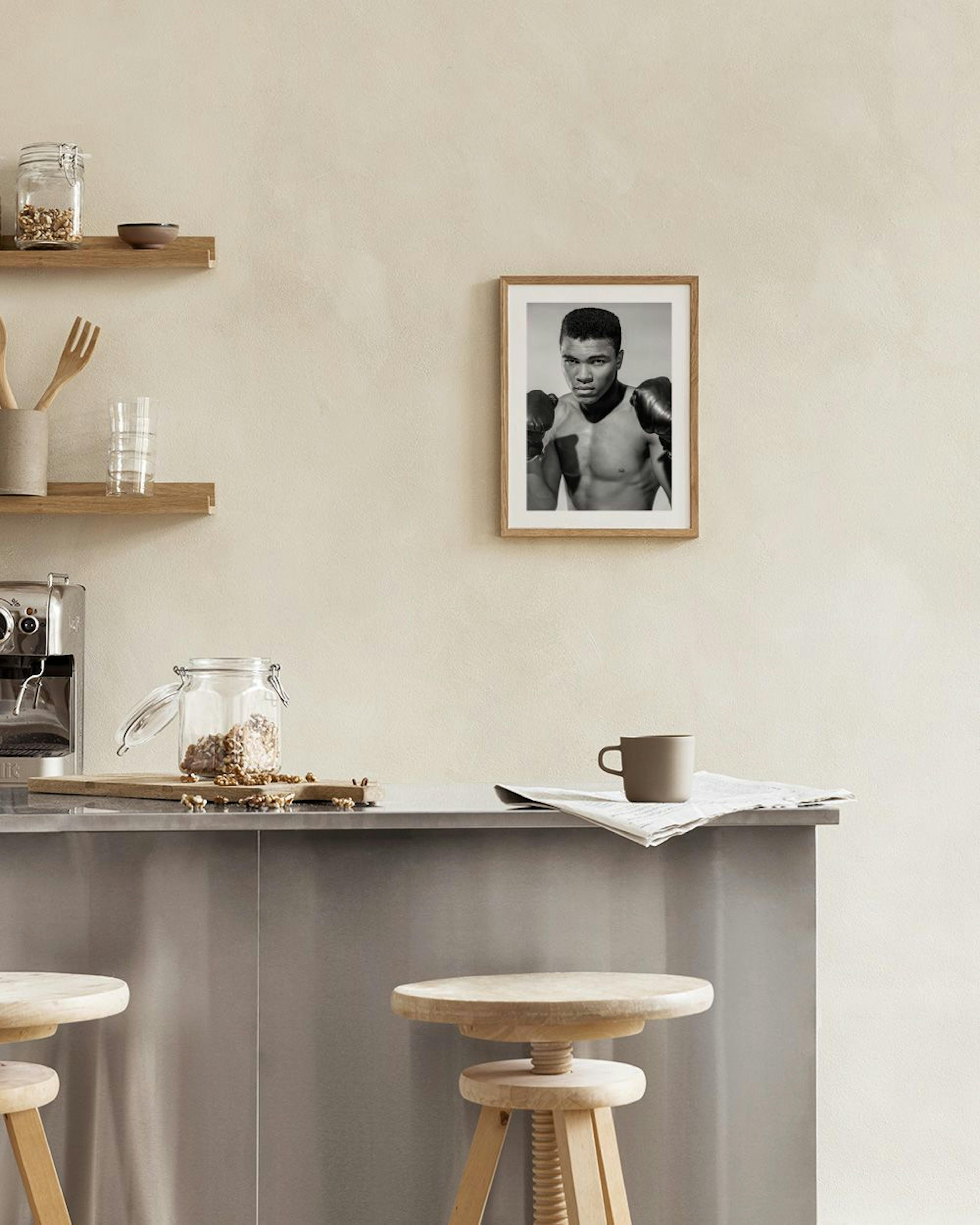 Schwarz-Weiß Poster von Muhammad Ali mit Boxhandschuhen, über einem beigen Sessel in einem modernen Wohnzimmer.