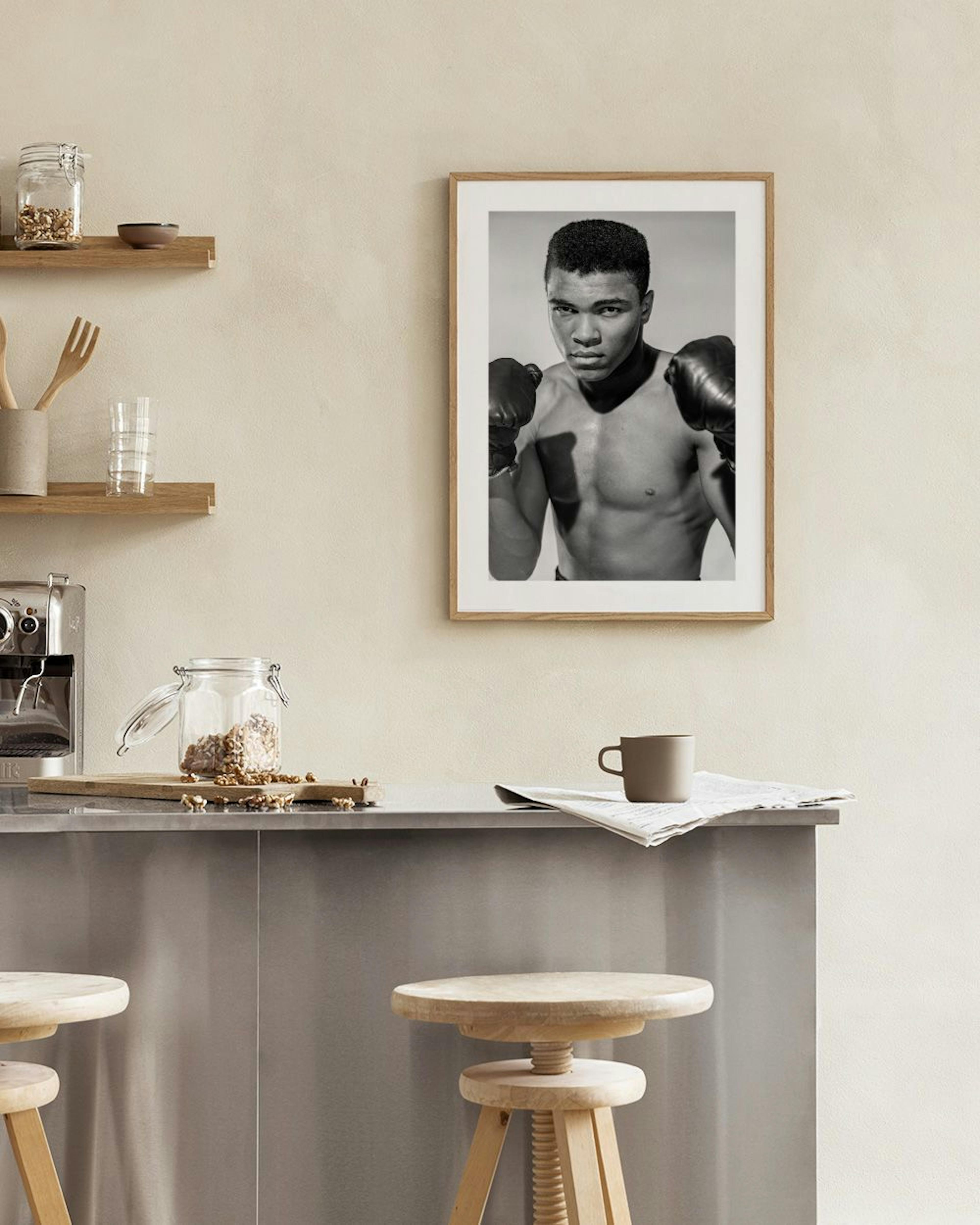 Póster en blanco y negro de Muhammad Ali con guantes de boxeo, colgado sobre un sillón en una sala de estar.
