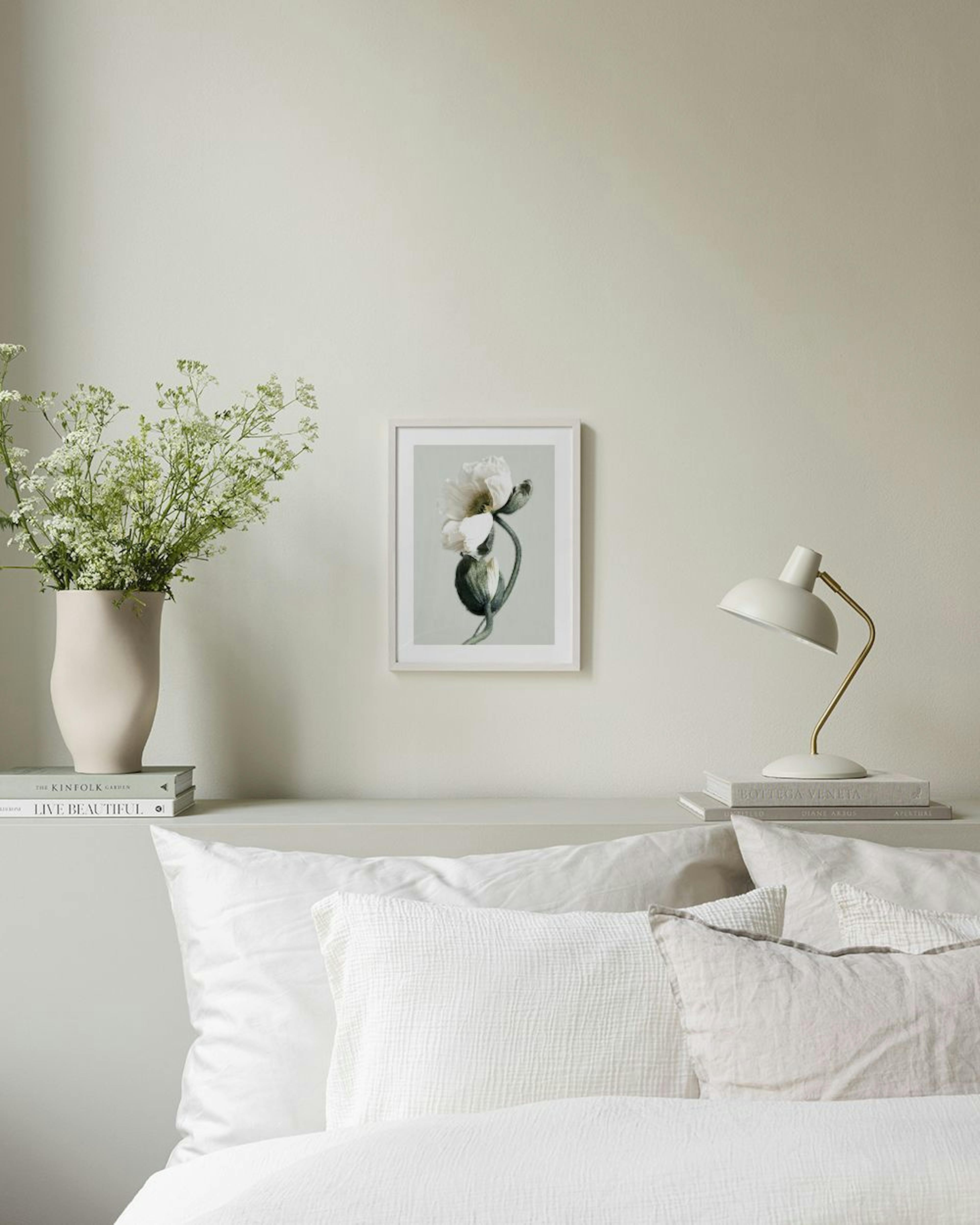 Poster mit weißer Mohnblume und Knospe an einer grauen Wand, über einer Bank mit Vase und Schale.
