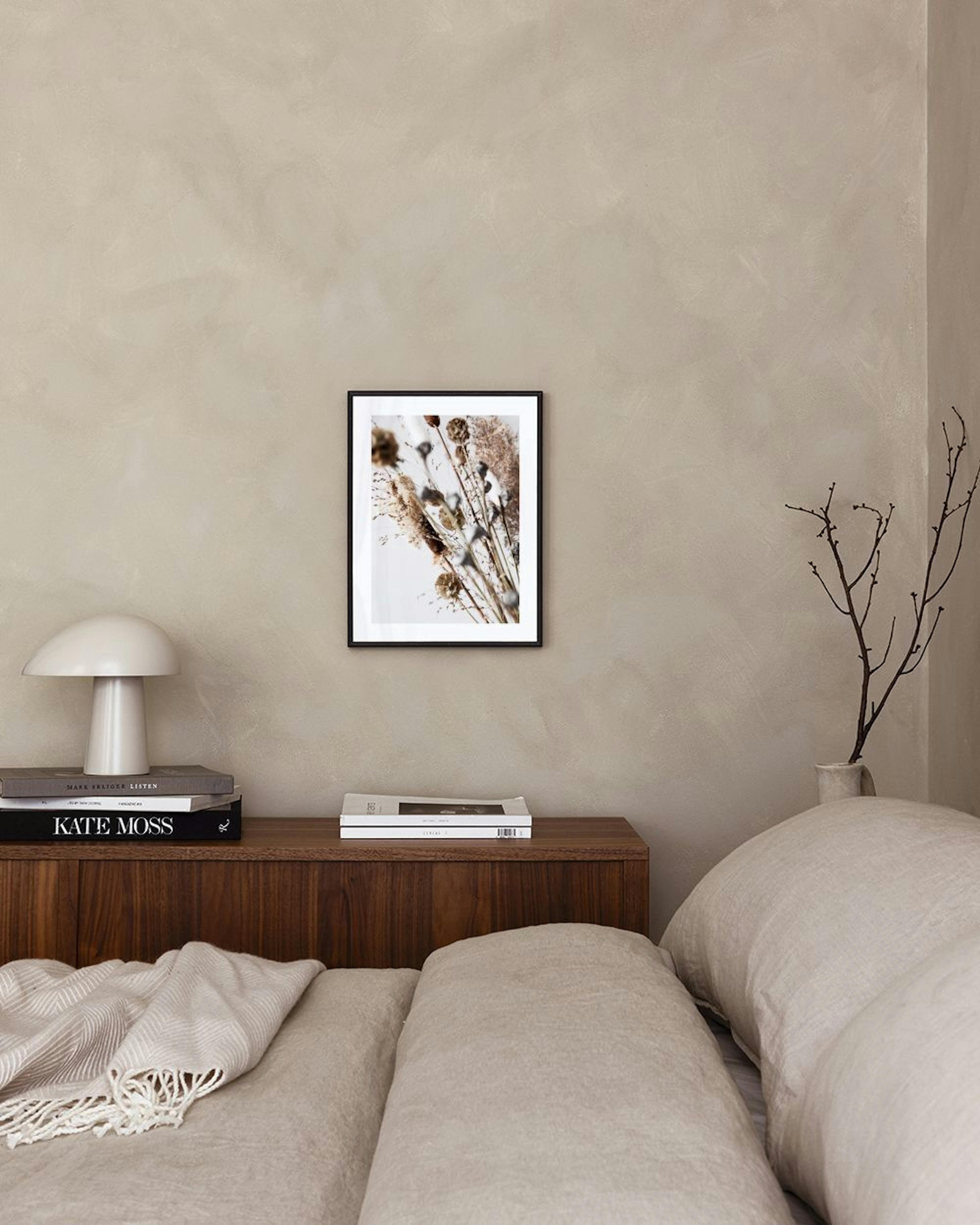 Póster de plantas secas y pasto en tonos tierra, exhibido sobre una repisa de concreto con jarrones en una habitación moderna.
