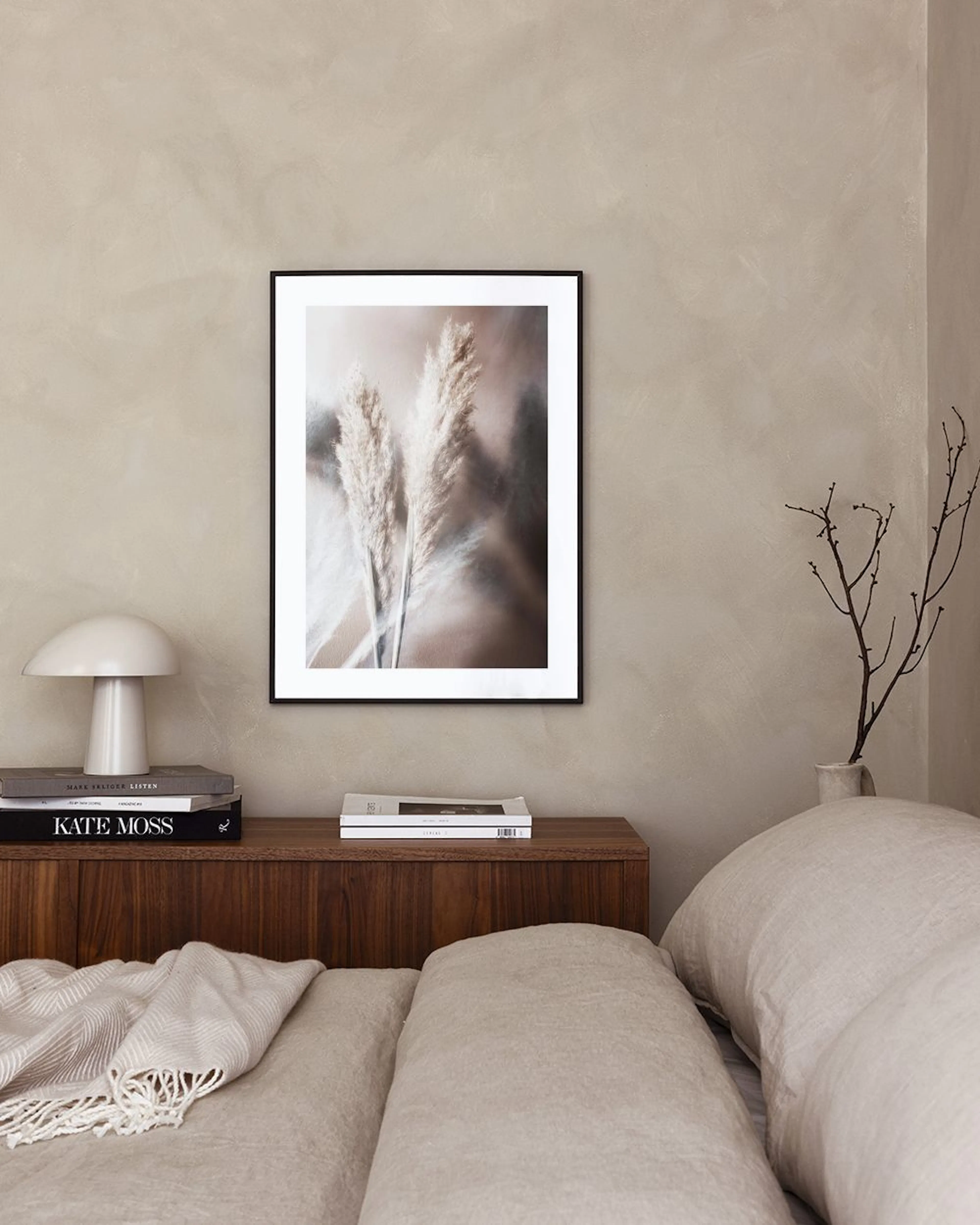 Affiche de trois épis de pampa aux teintes neutres, accrochée au-dessus dun bureau en bois clair avec un vase.