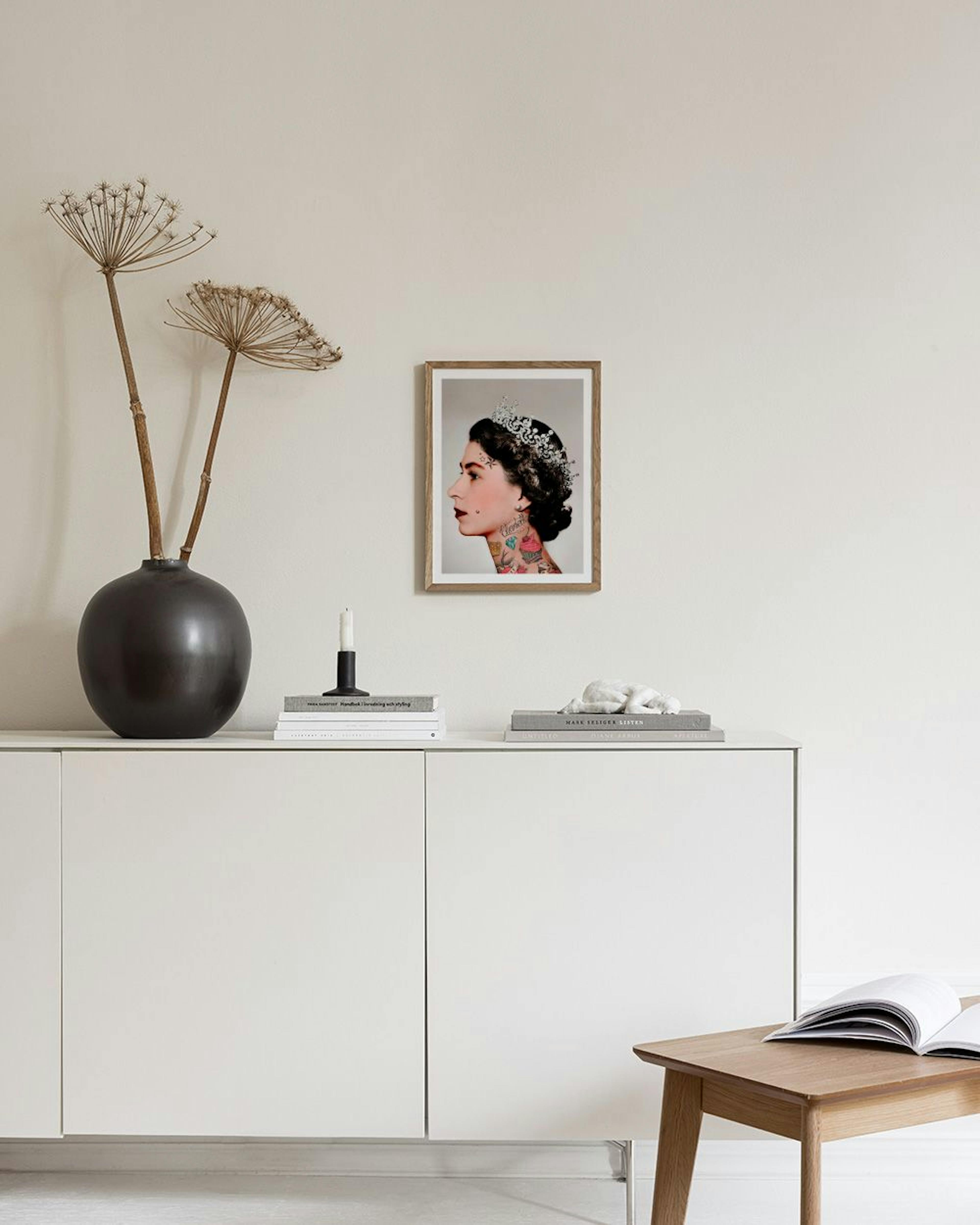 Poster einer tätowierten Königin Elisabeth II. mit Diadem, über einem Sideboard mit blauen Vasen.
