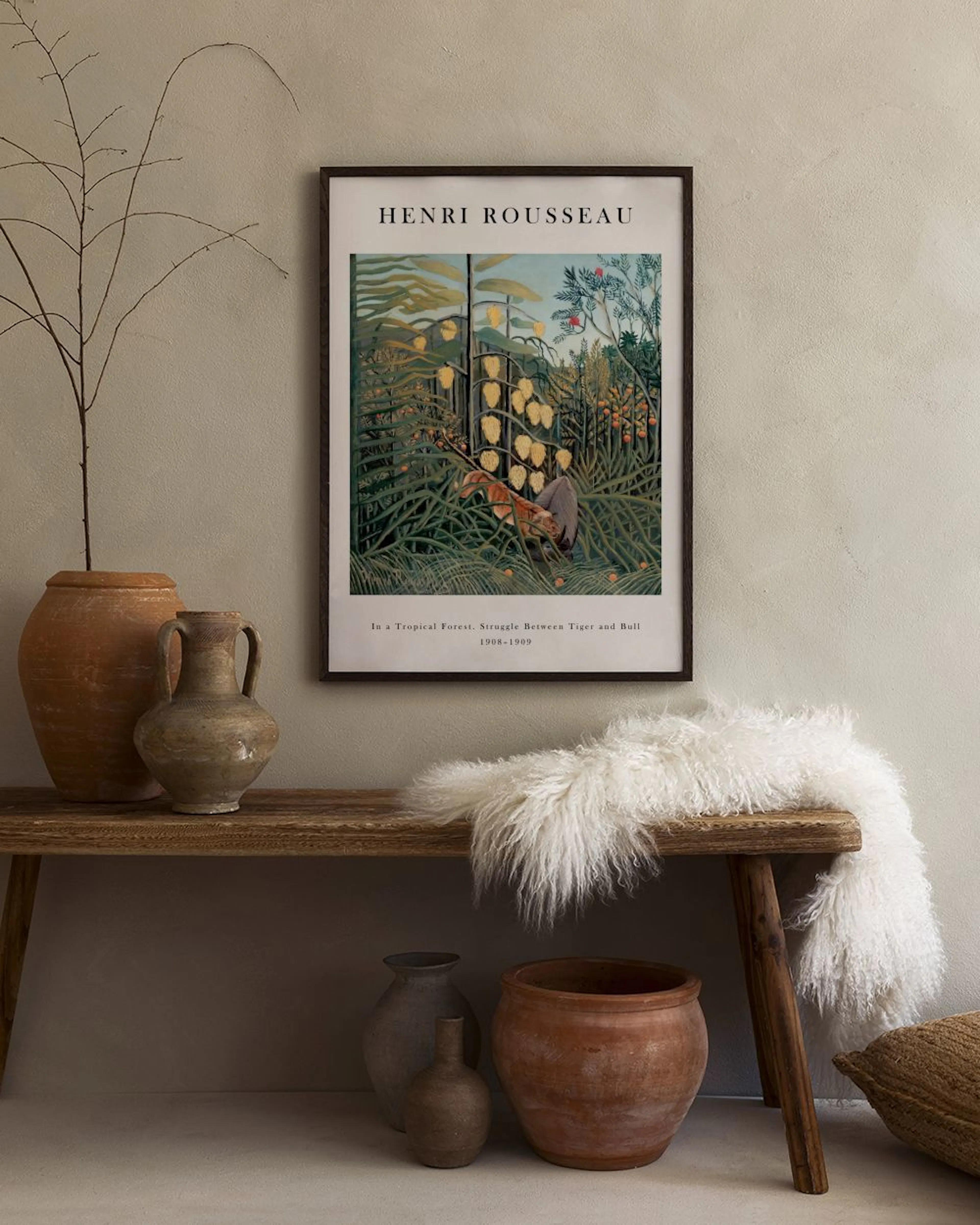 A Henri Rousseau jungle print with tigers and bull, hanging above a white marble table with two white vases and books.