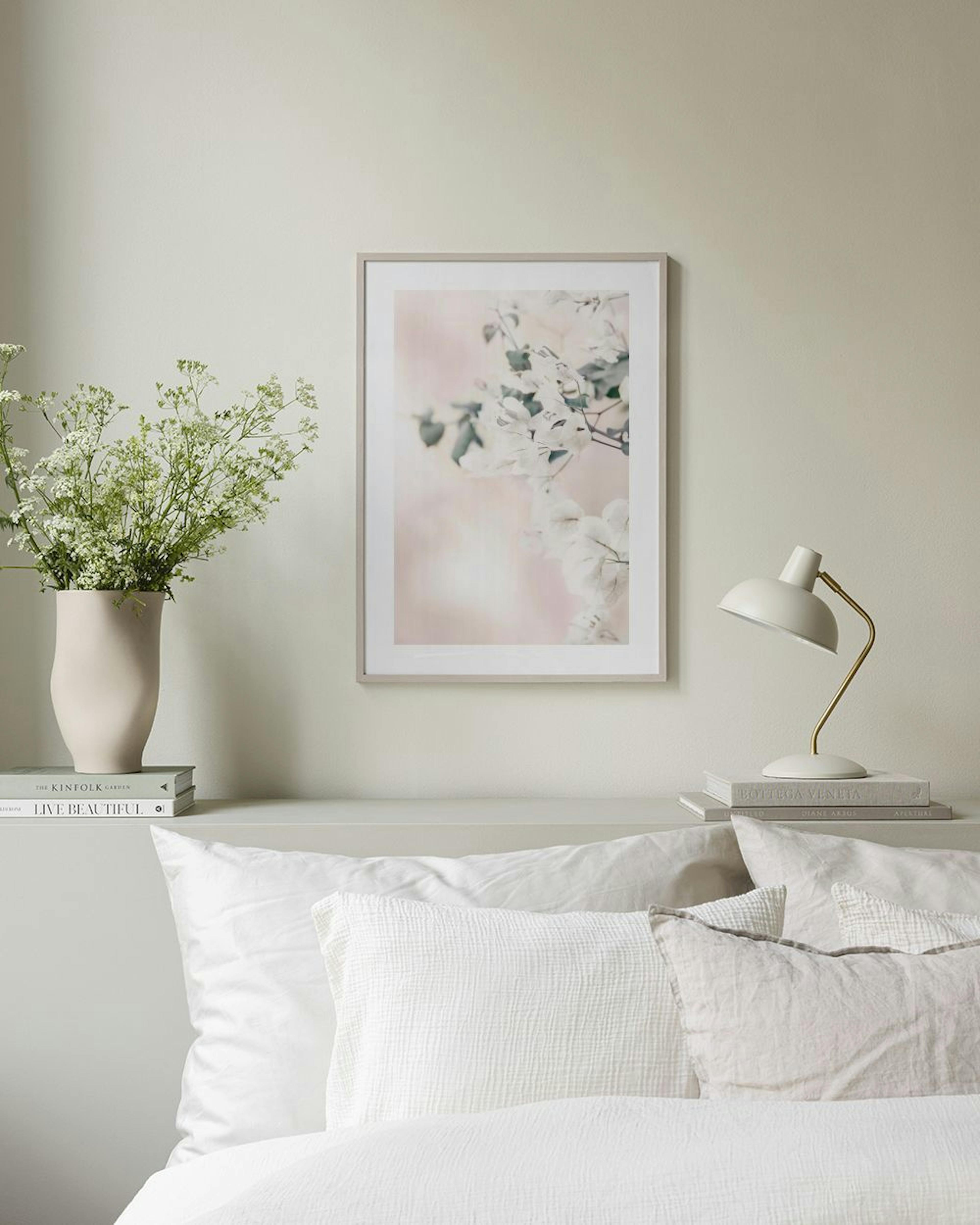 Poster mit zarten weissen Blüten und grünen Blättern auf rosafarbenem Hintergrund, hängt über einem mintgrünen Sofa.