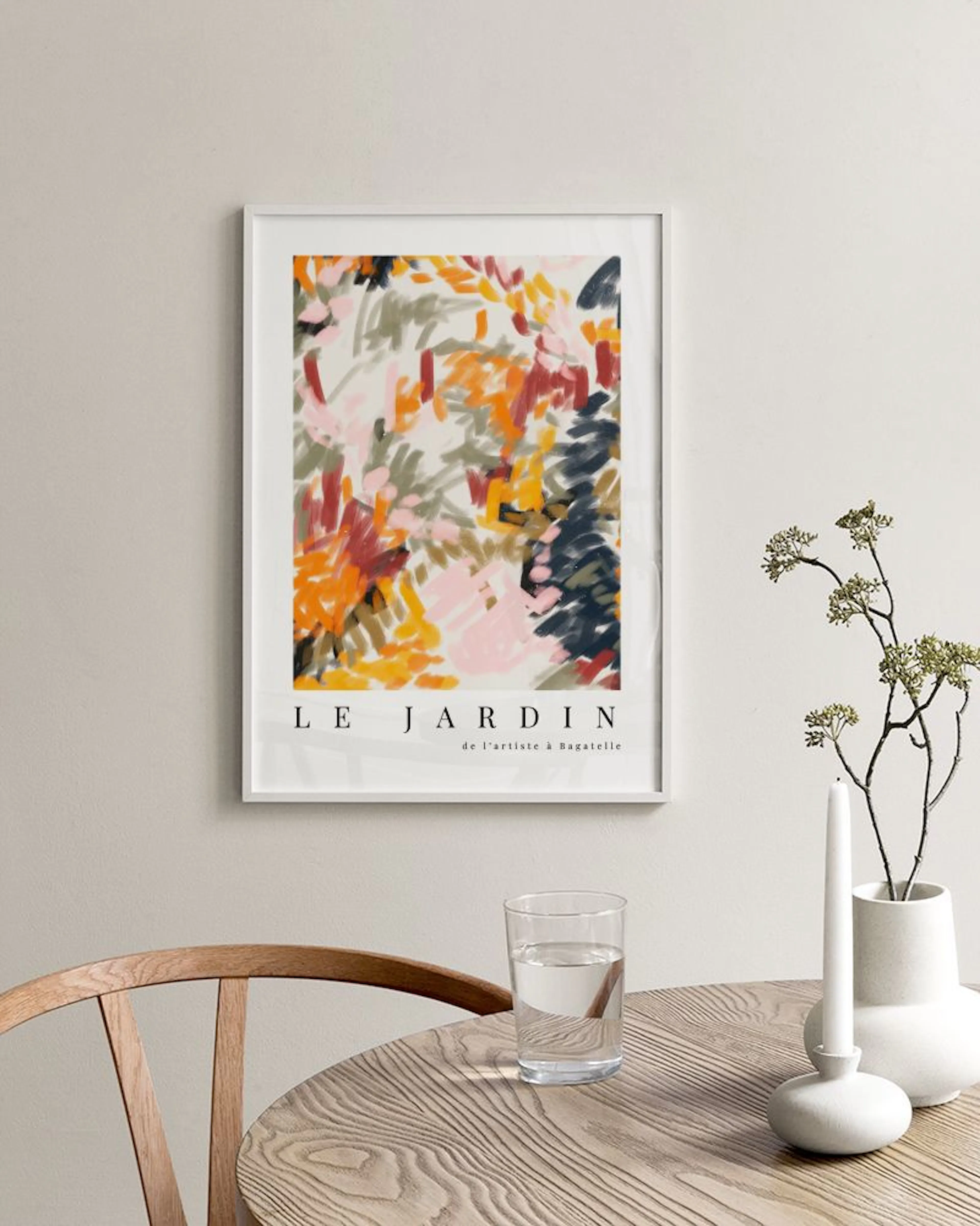 Abstrakt poster med penseldrag i rött, orange, gult och mörkblått, text Le Jardin, placerad på en vit byrå.