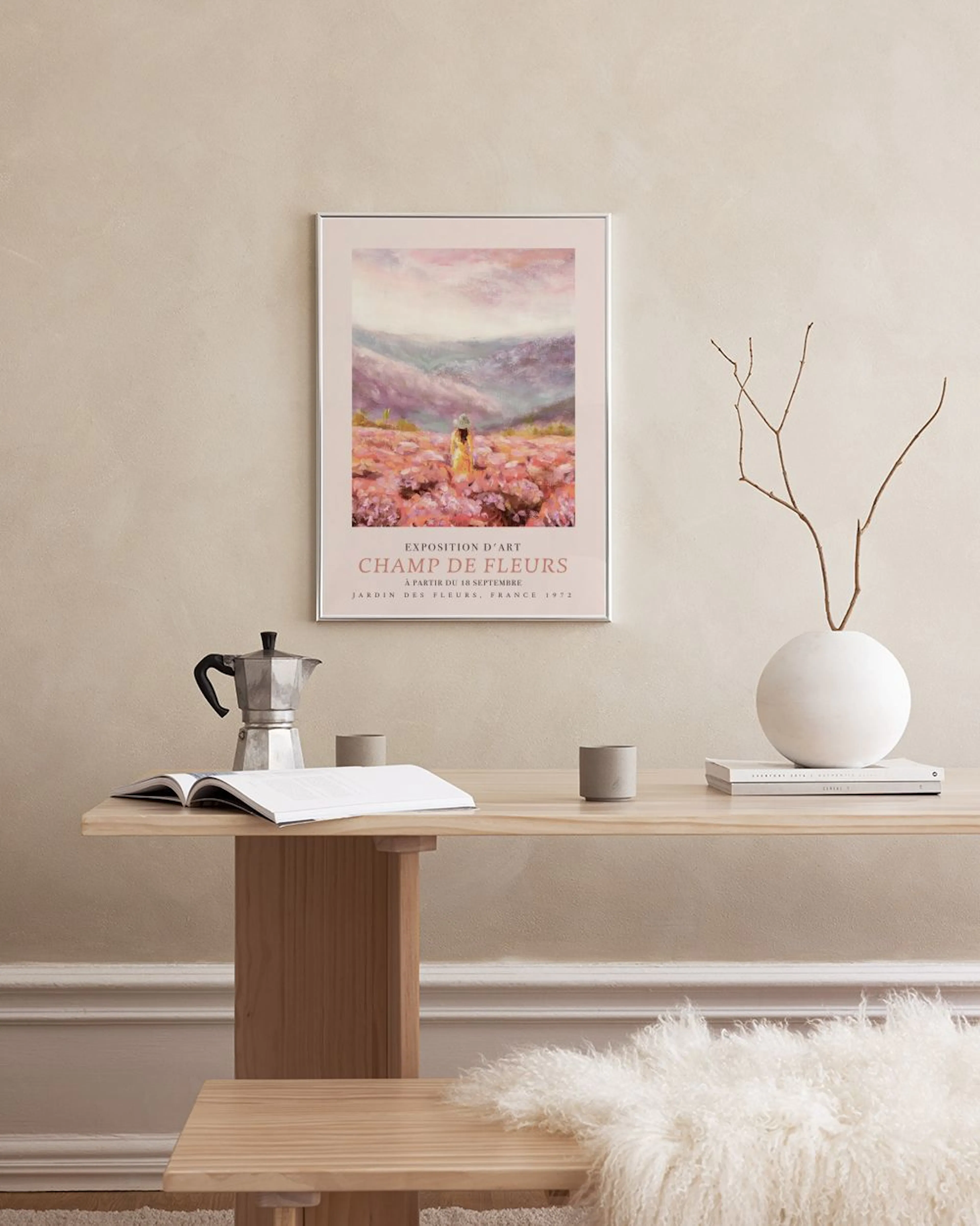 Poster med en kvinna i ett lila blomsterfält framför berg, hängandes ovanför ett vitt marmorbord med vaser.