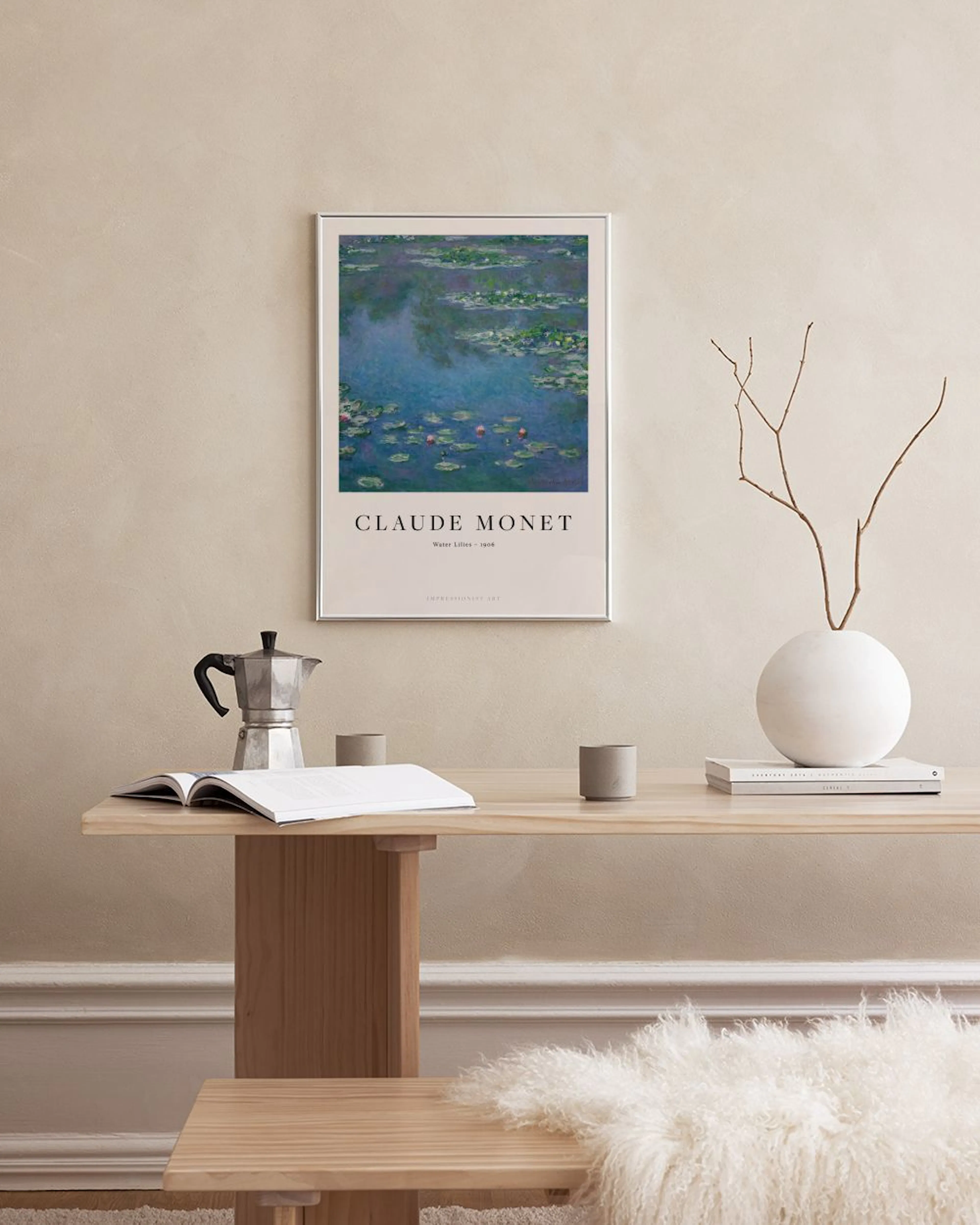 Poster con ninfee blu e rosse di Claude Monet, appeso sopra un mobile bianco con vasi e libri.