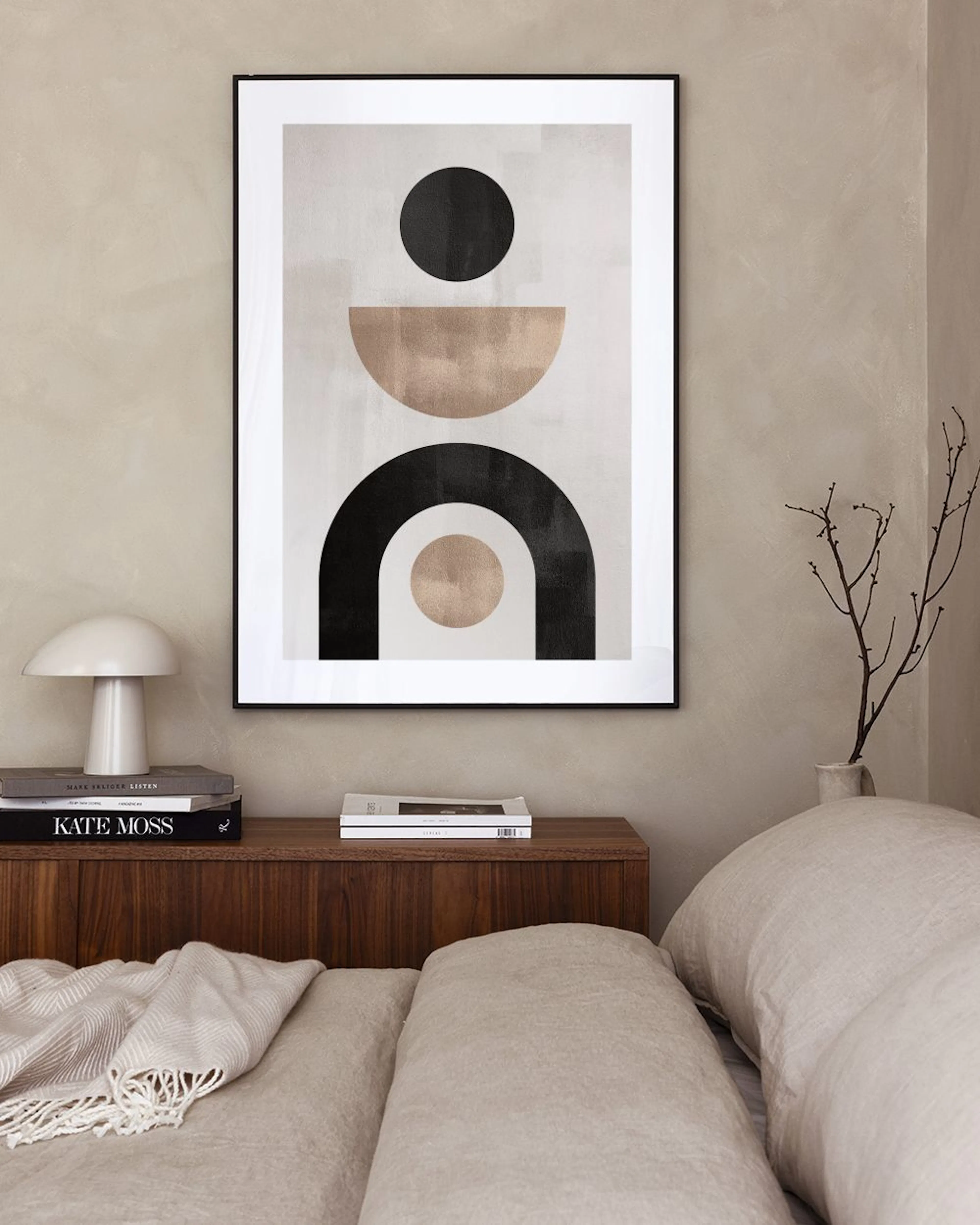 A print of black and beige abstract geometric shapes, hanging above a white cabinet with decorative vases and books.