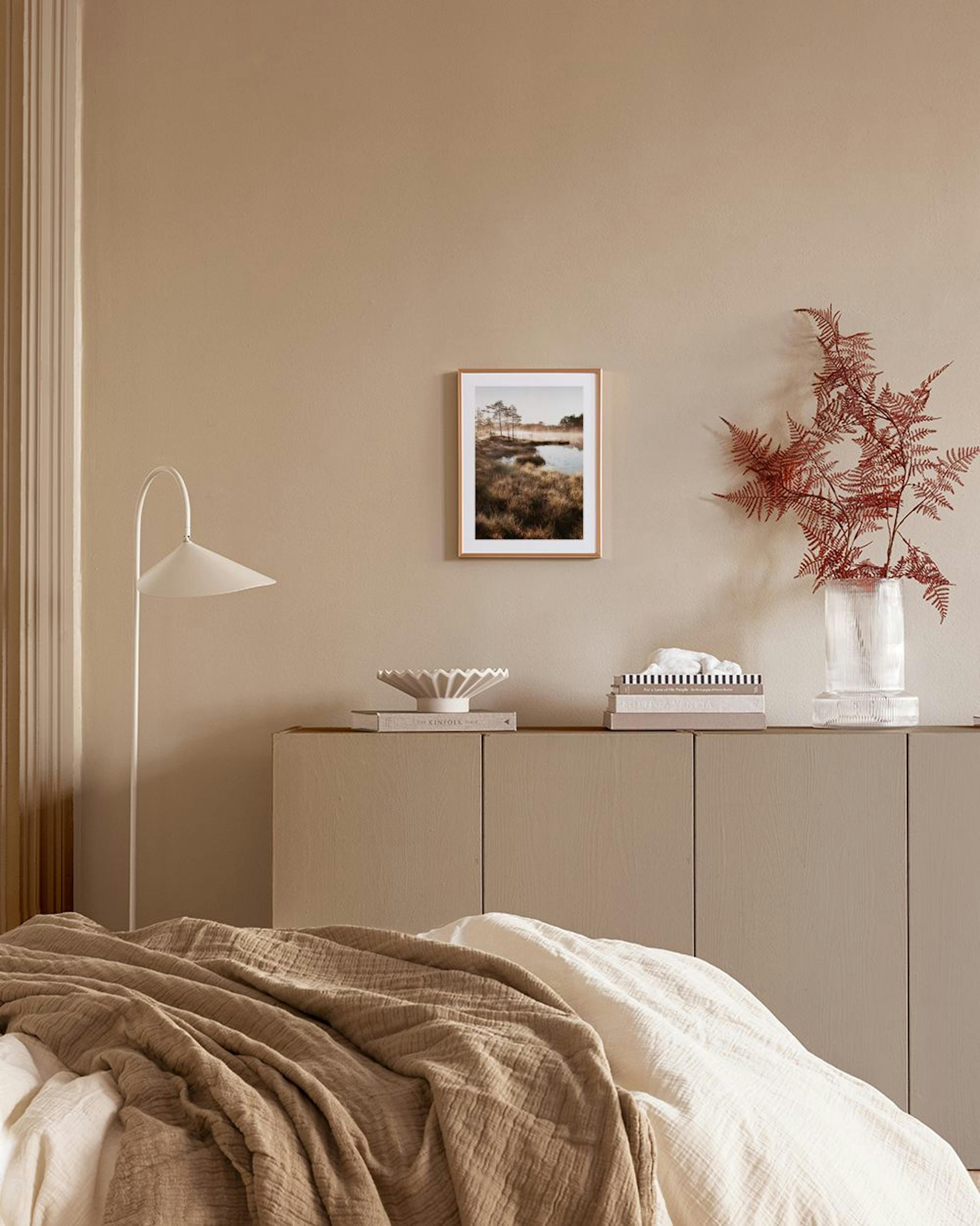Poster van een mistige ochtend over een moeras met dennenbomen, hangend boven een houten dressoir met vazen en boeken.