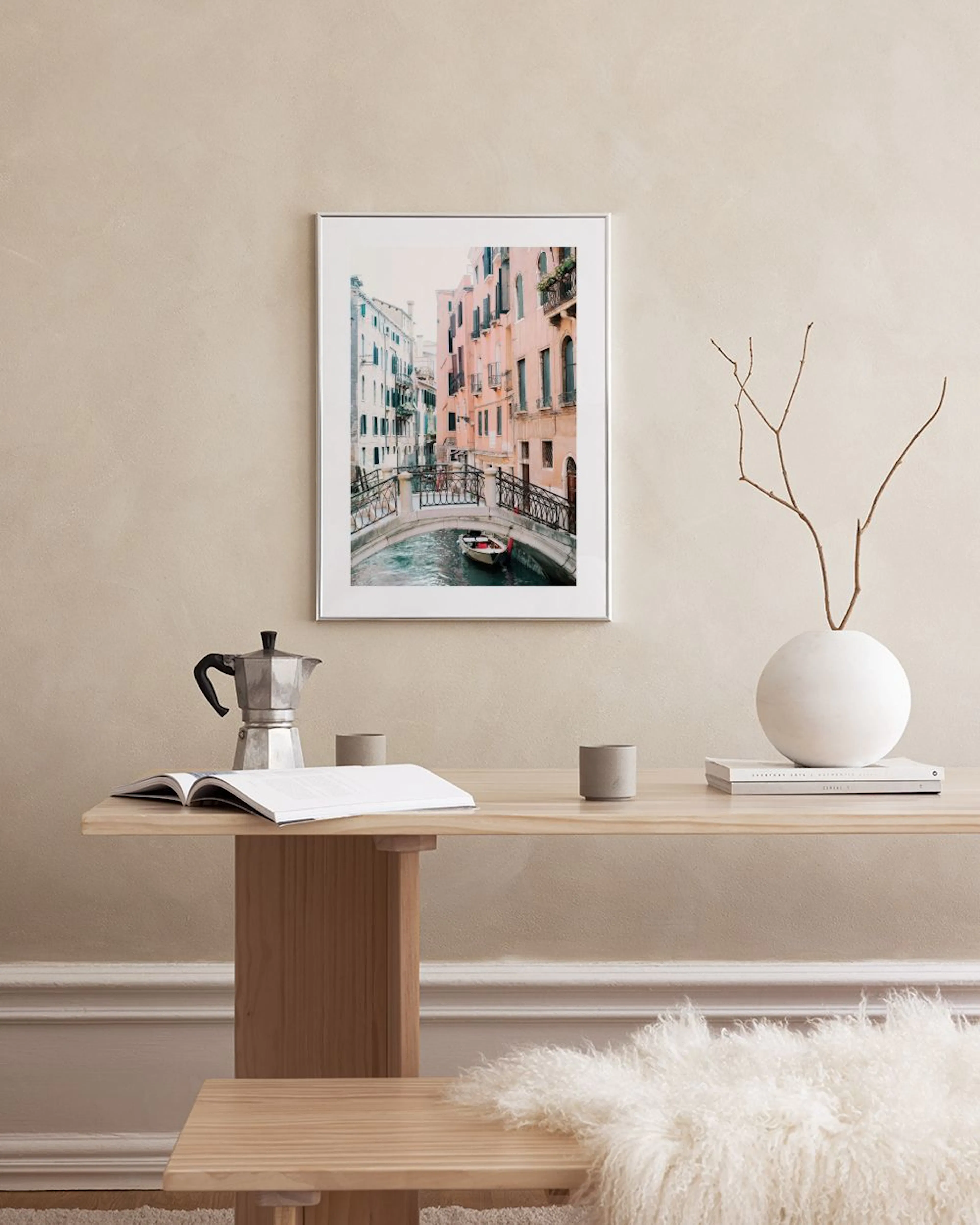 Affiche de Venise avec un pont au-dessus dun canal et de vieux bâtiments colorés, suspendue au-dessus dune table noire.