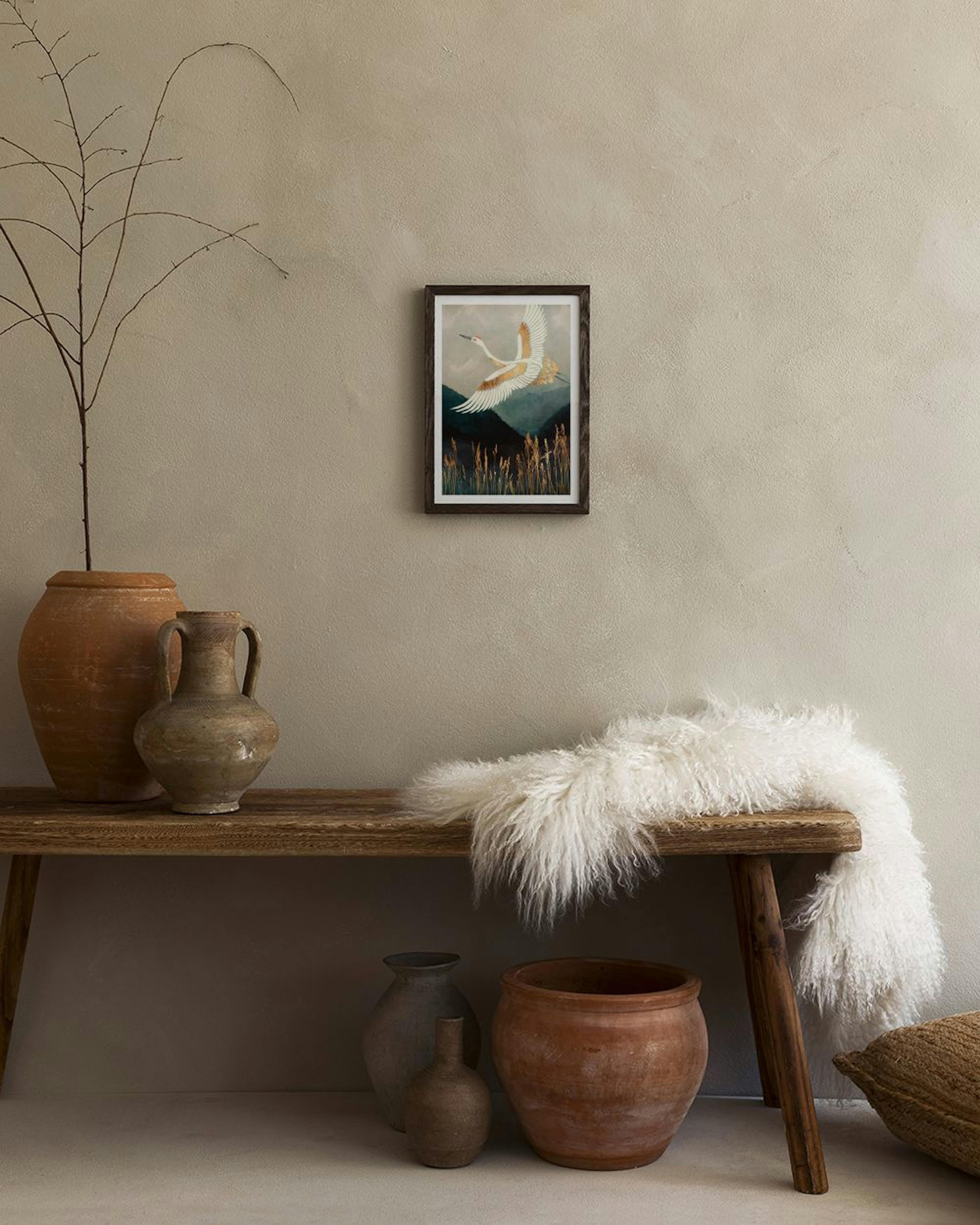 Affiche dune grue blanche et dorée volant au-dessus de montagnes et herbes, affichée dans un salon moderne.