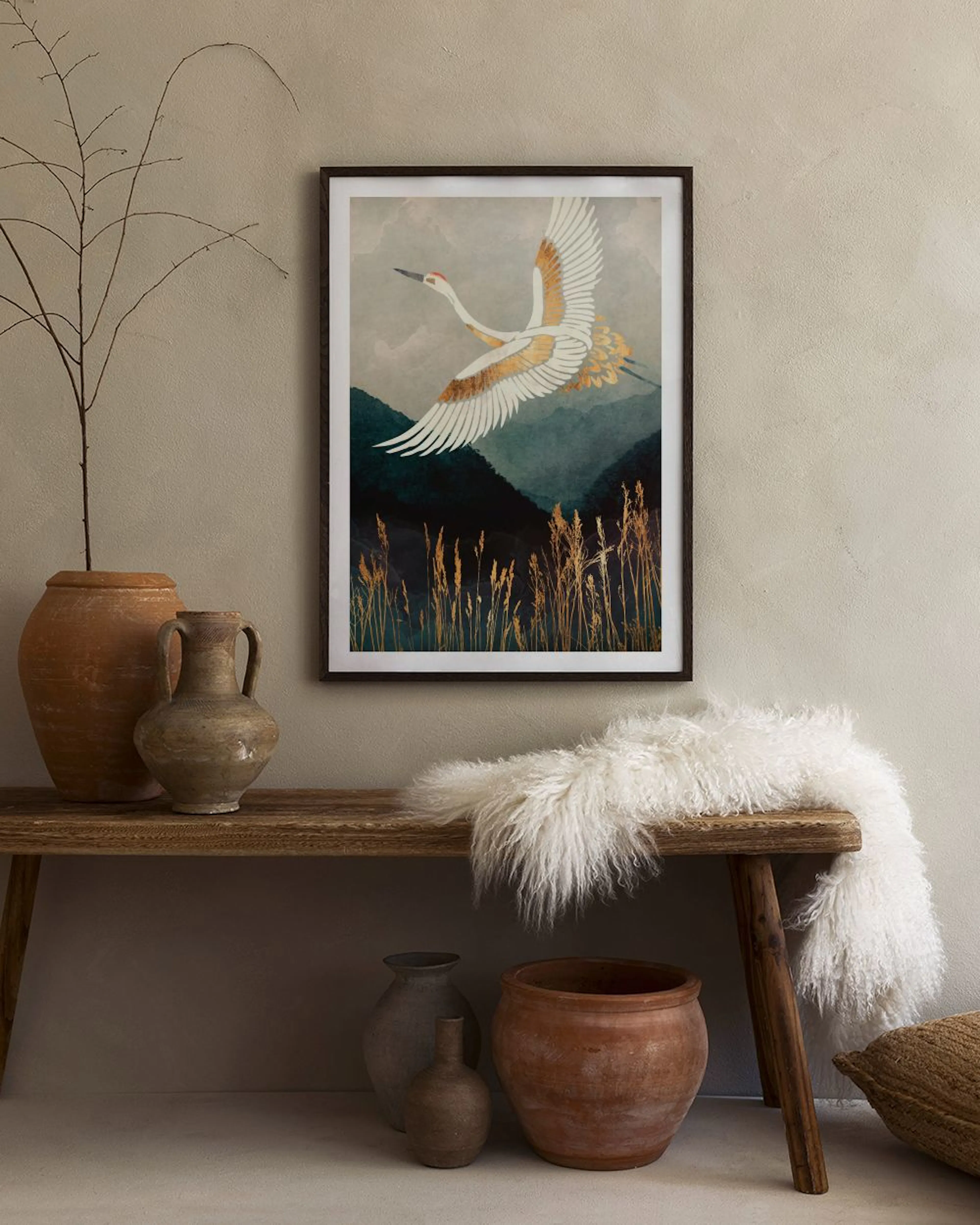 A stunning print of a white crane with golden wings soaring over a dark green landscape with golden reeds, displayed on a grey w