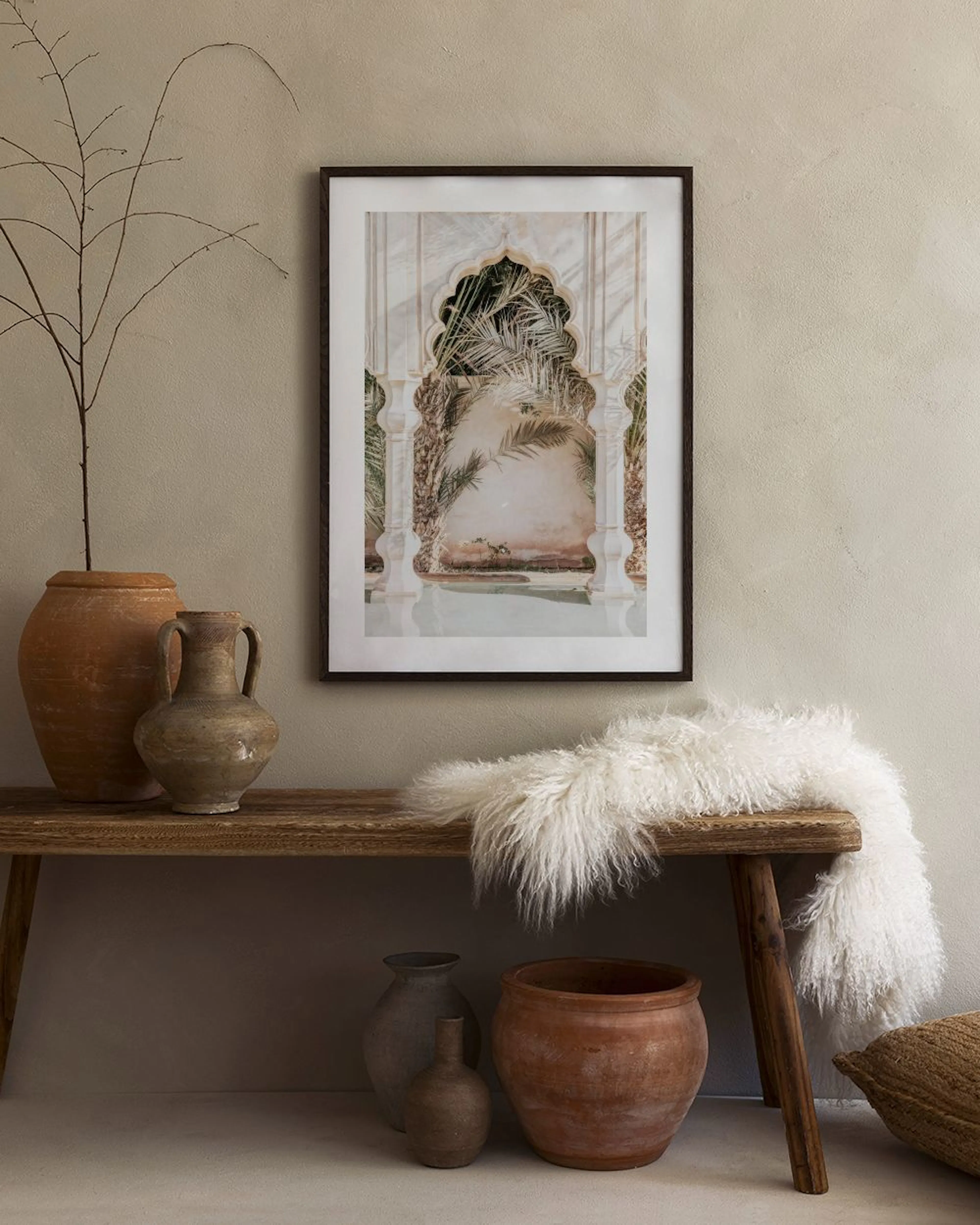 Affiche dune arche ornée avec feuilles de palmier, suspendue au-dessus dun meuble en rotin clair dans un intérieur moderne.