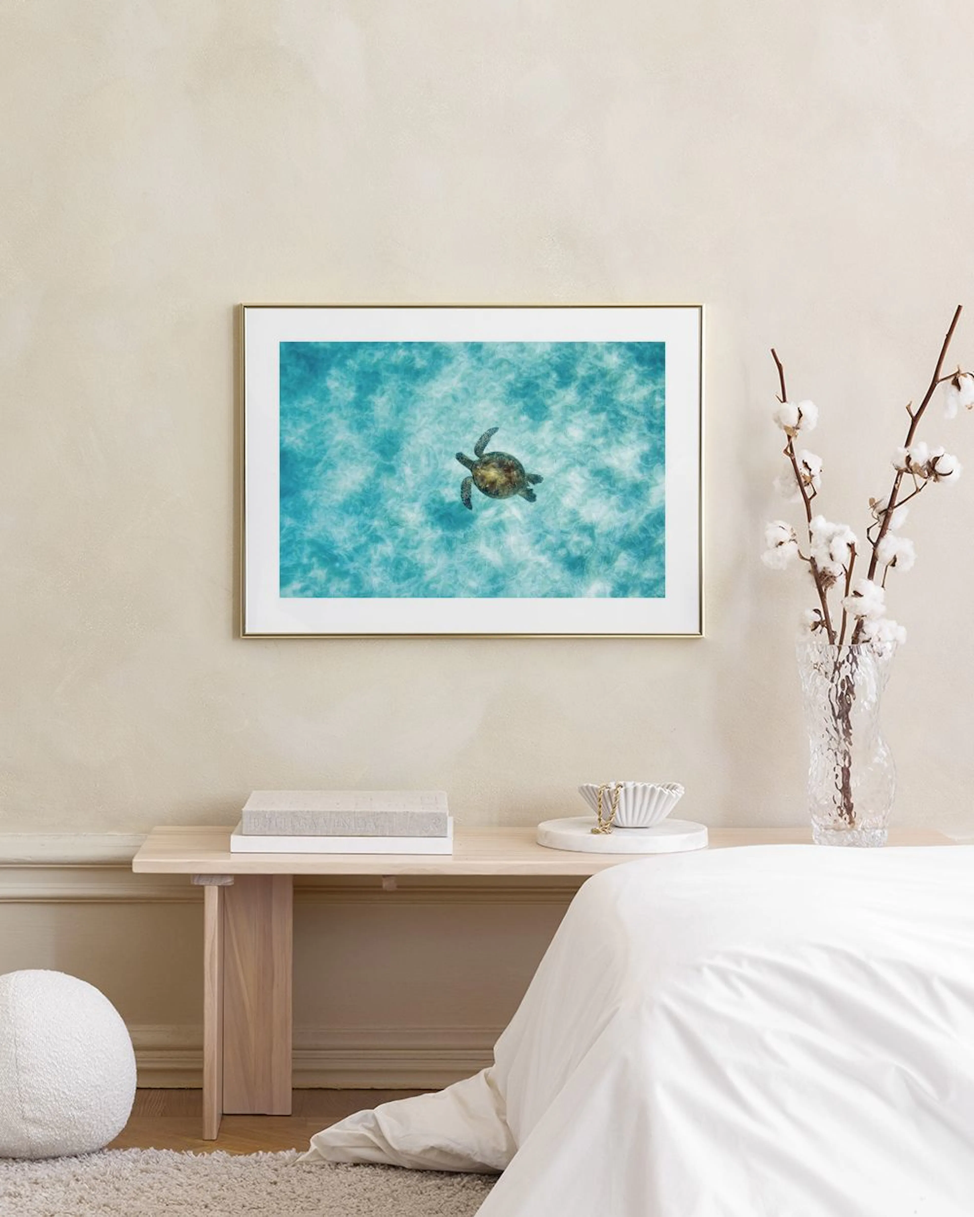 A serene print of a sea turtle swimming in clear blue water, displayed above a white cabinet in a home setting.