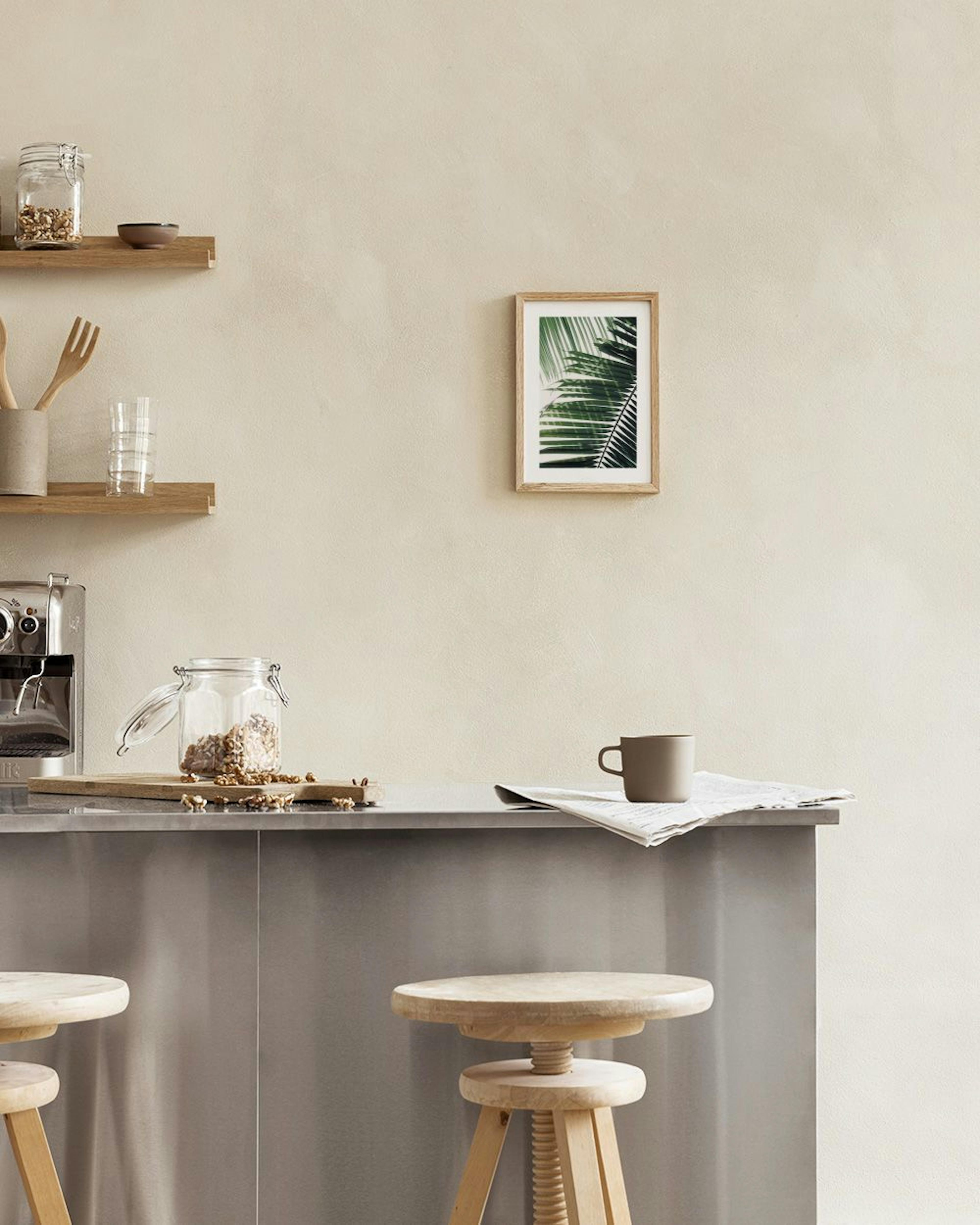 Affiche de feuilles de palmier vertes foncées et claires sur fond blanc, suspendue au-dessus dune table basse en bois.