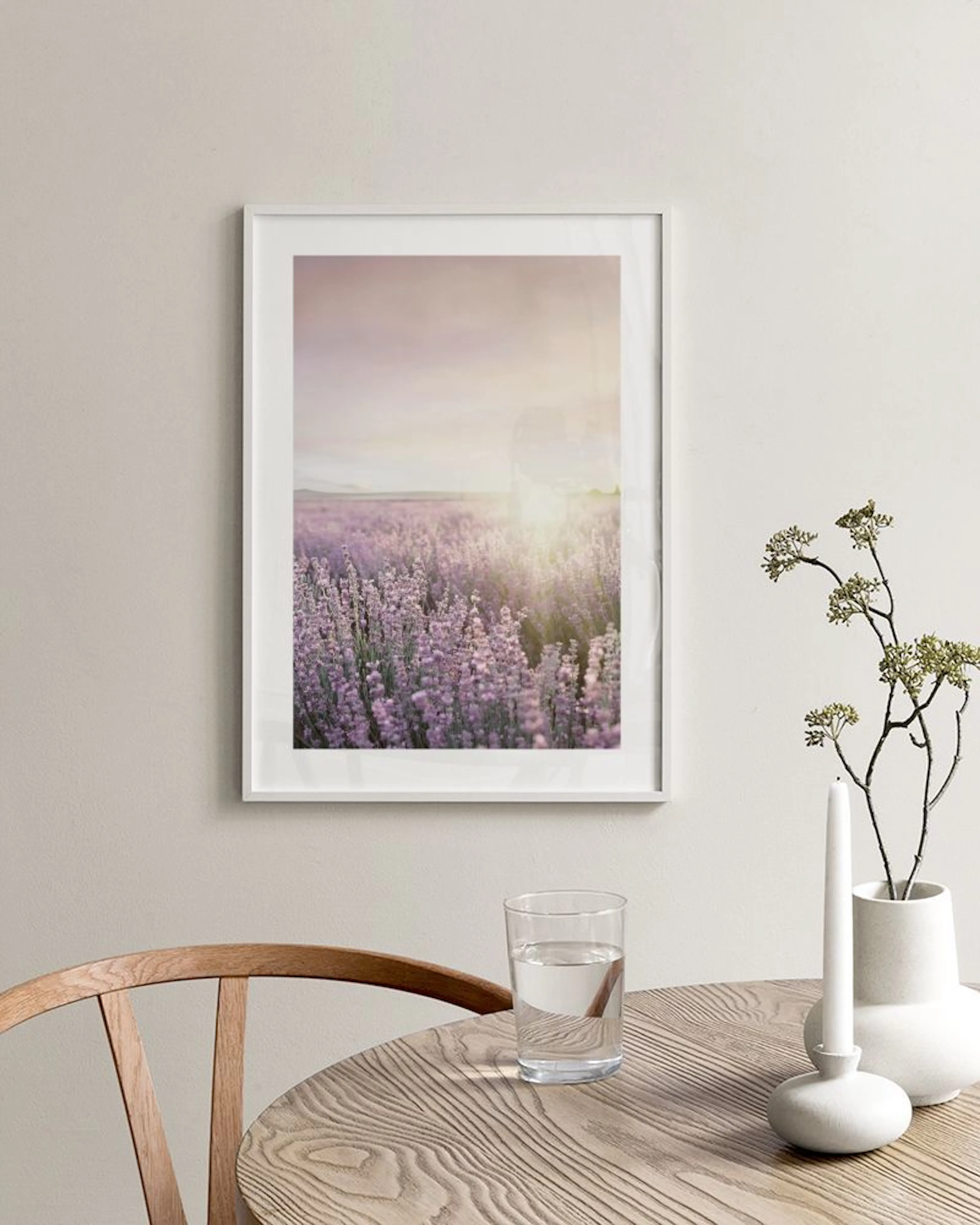 Plakat med lilla lavendelåker i solnedgang, henger over et betongbord ved en seng og plante.