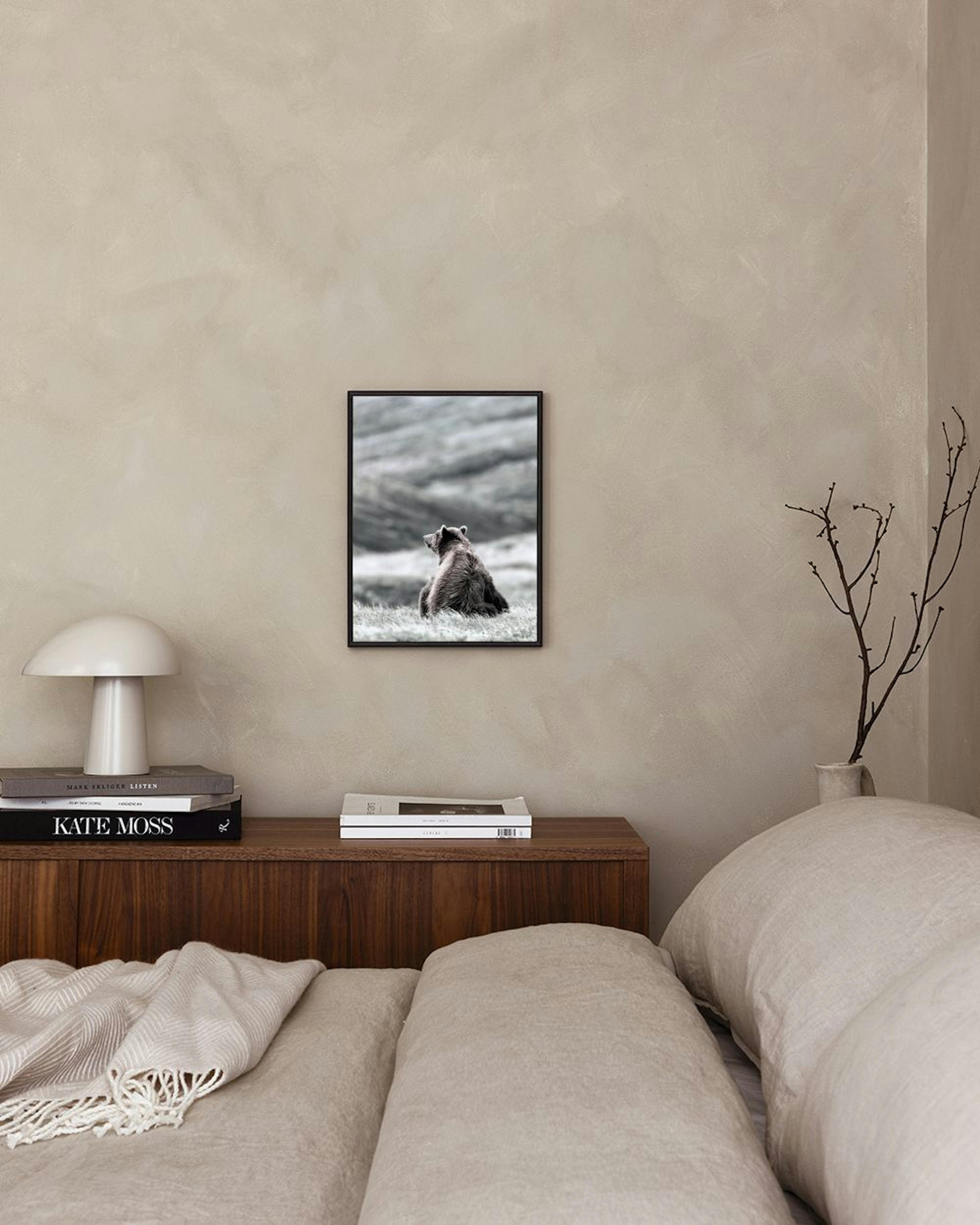 Affiche dun ours brun assis dans lherbe, accrochée au-dessus dun tabouret avec des livres dans un salon moderne.