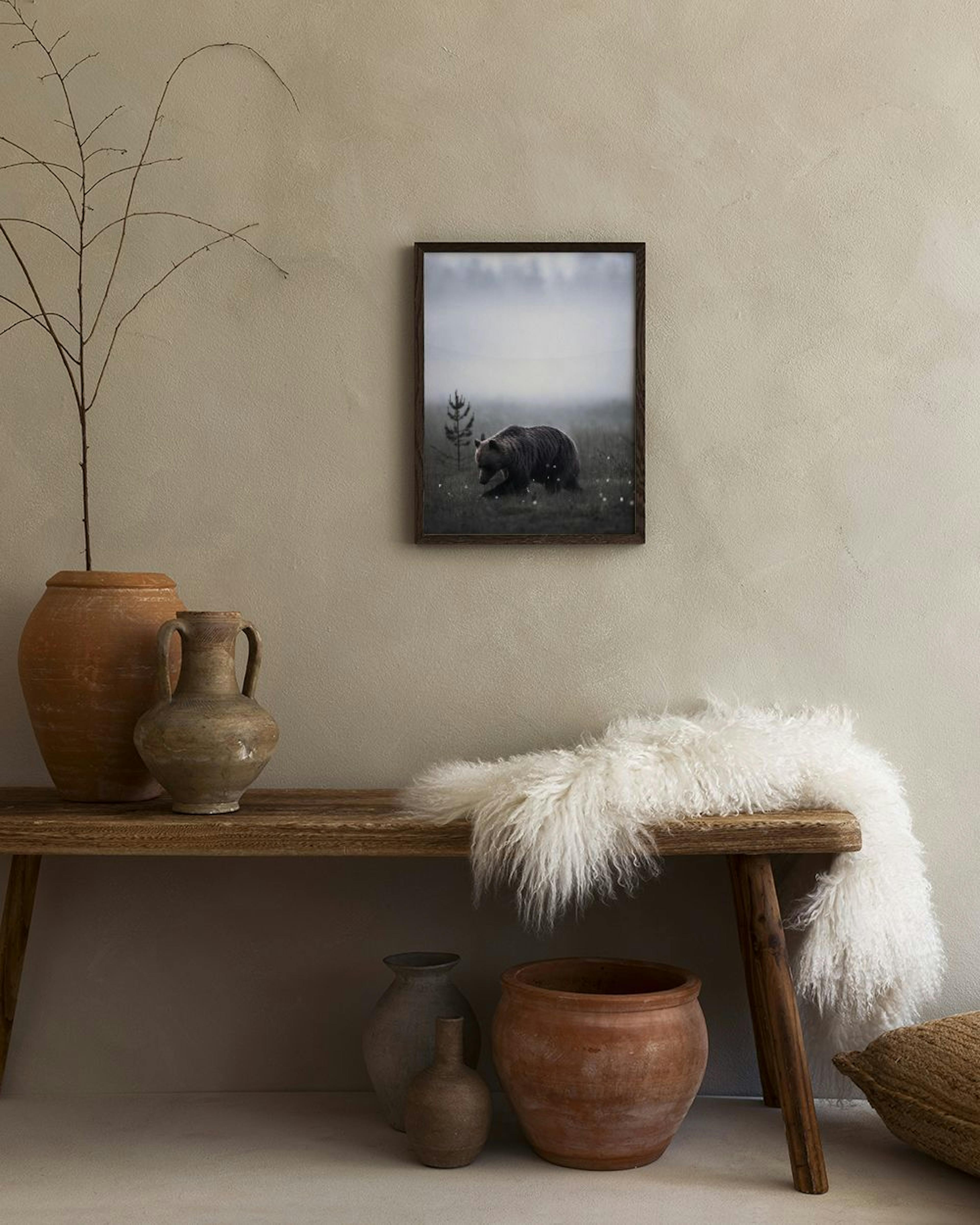 Poster van een bruine beer in een mistig veld met een dennenboom, hangend boven een witte ladekast met vaas in een hal.