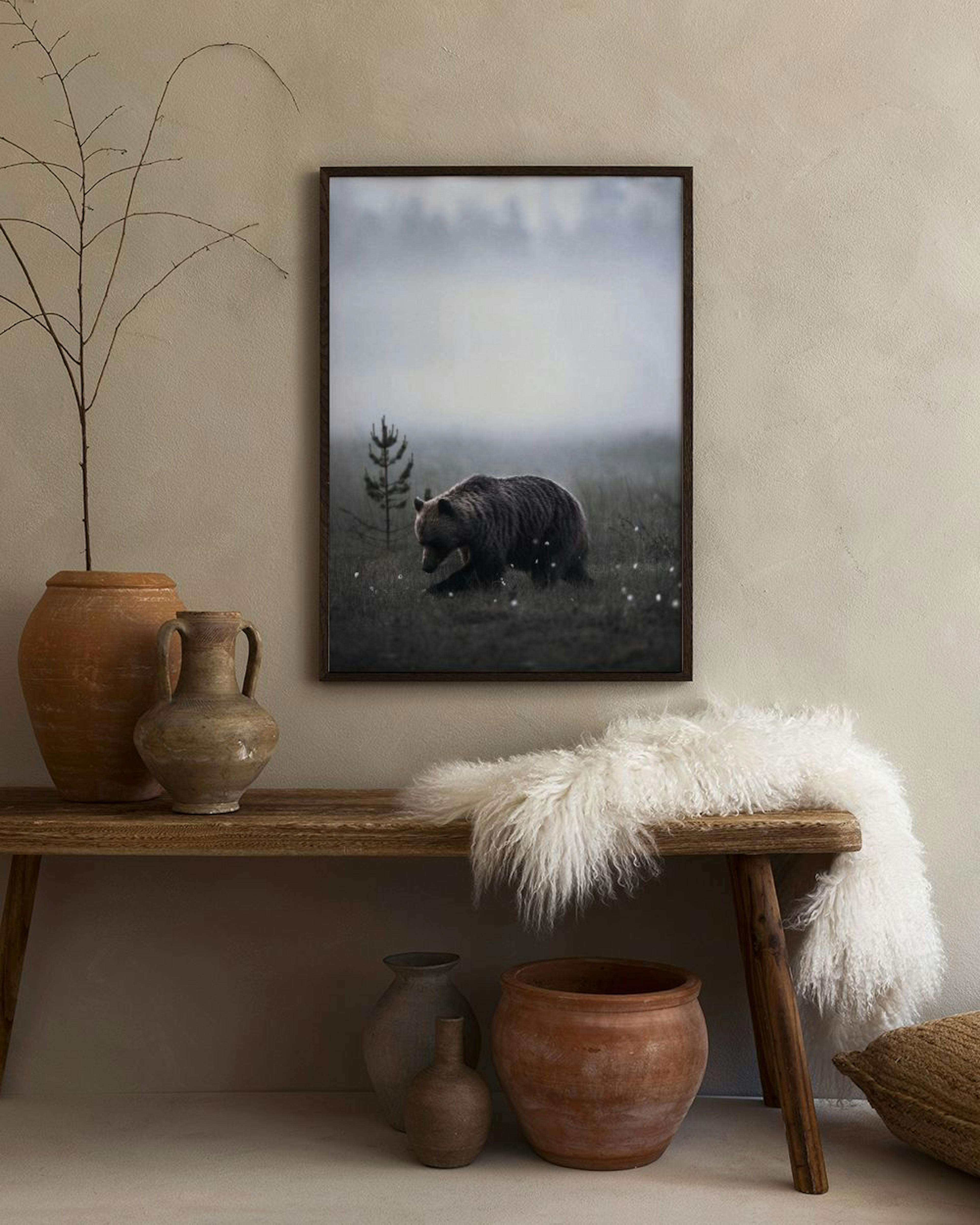 A print of a brown bear in a misty field, hanging on a white wall above a white cabinet with a gray vase.