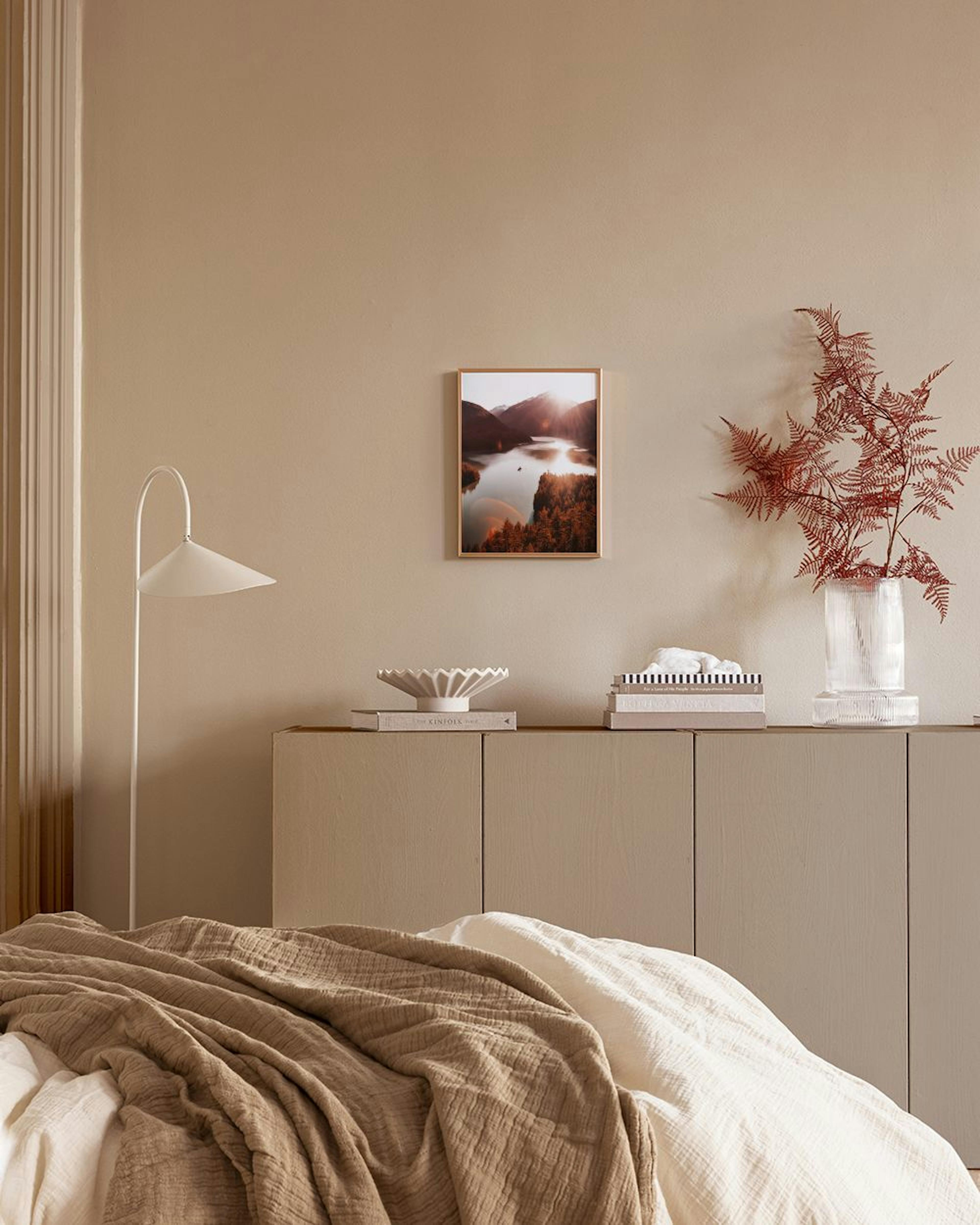 Affiche lac de montagne au coucher du soleil, avec arbres et reflets, accrochée au-dessus dun meuble blanc et dune chaise en cui