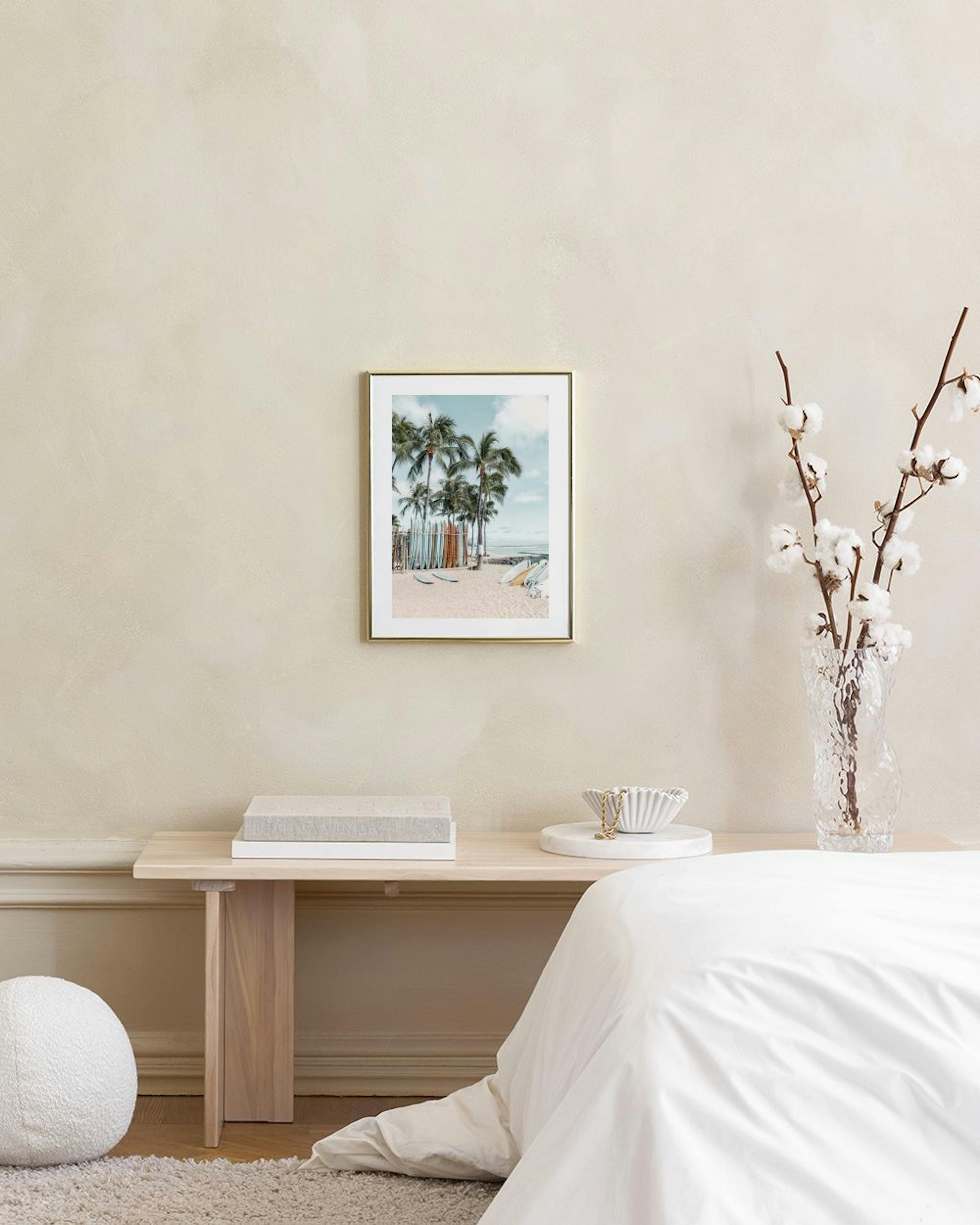 A print of palm trees and surfboards on a sandy beach, hanging above a white cabinet with decorative vases.