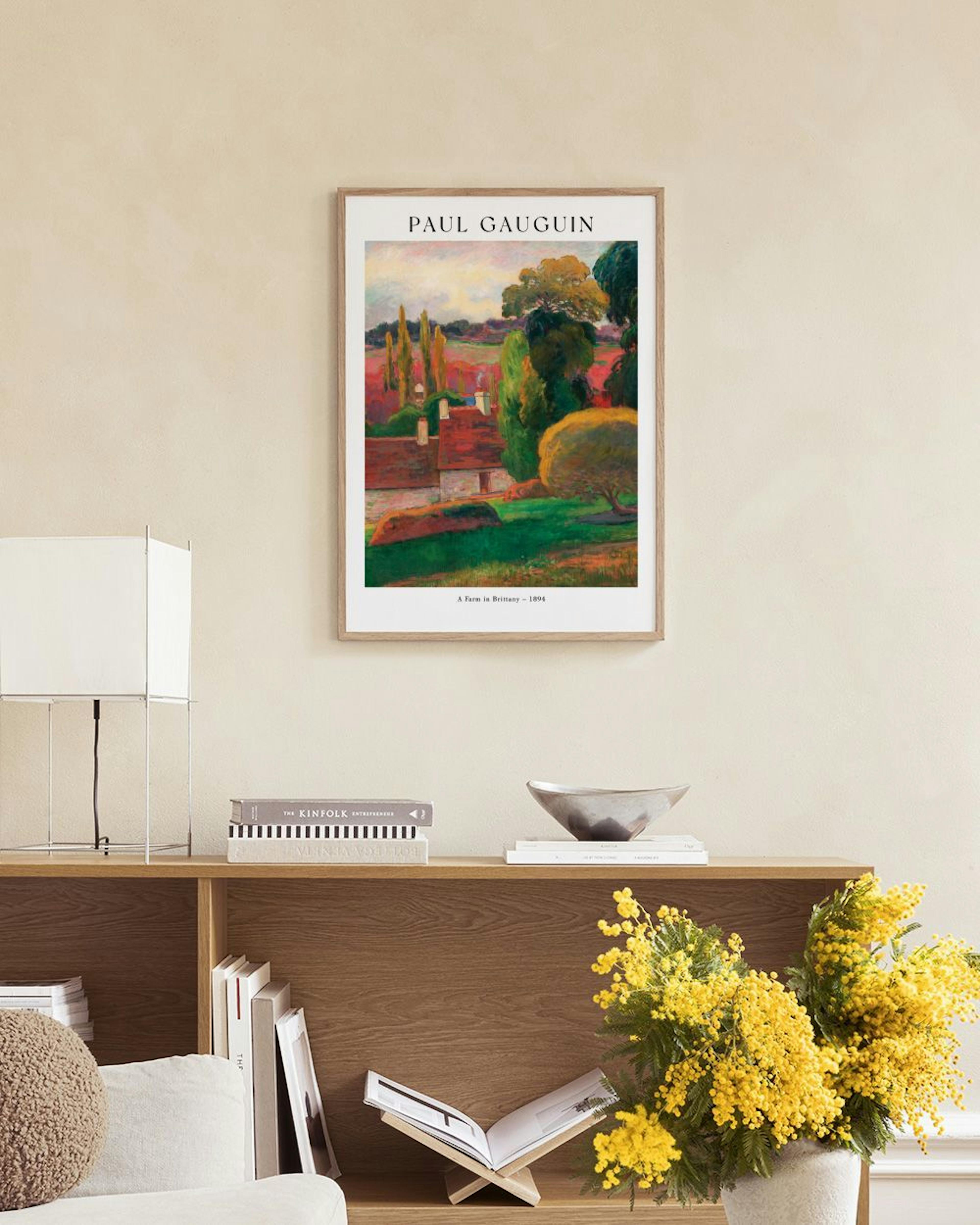 Gauguins A Farm In Brittany print, featuring houses, trees, and fields, hangs above a white cabinet in a room.