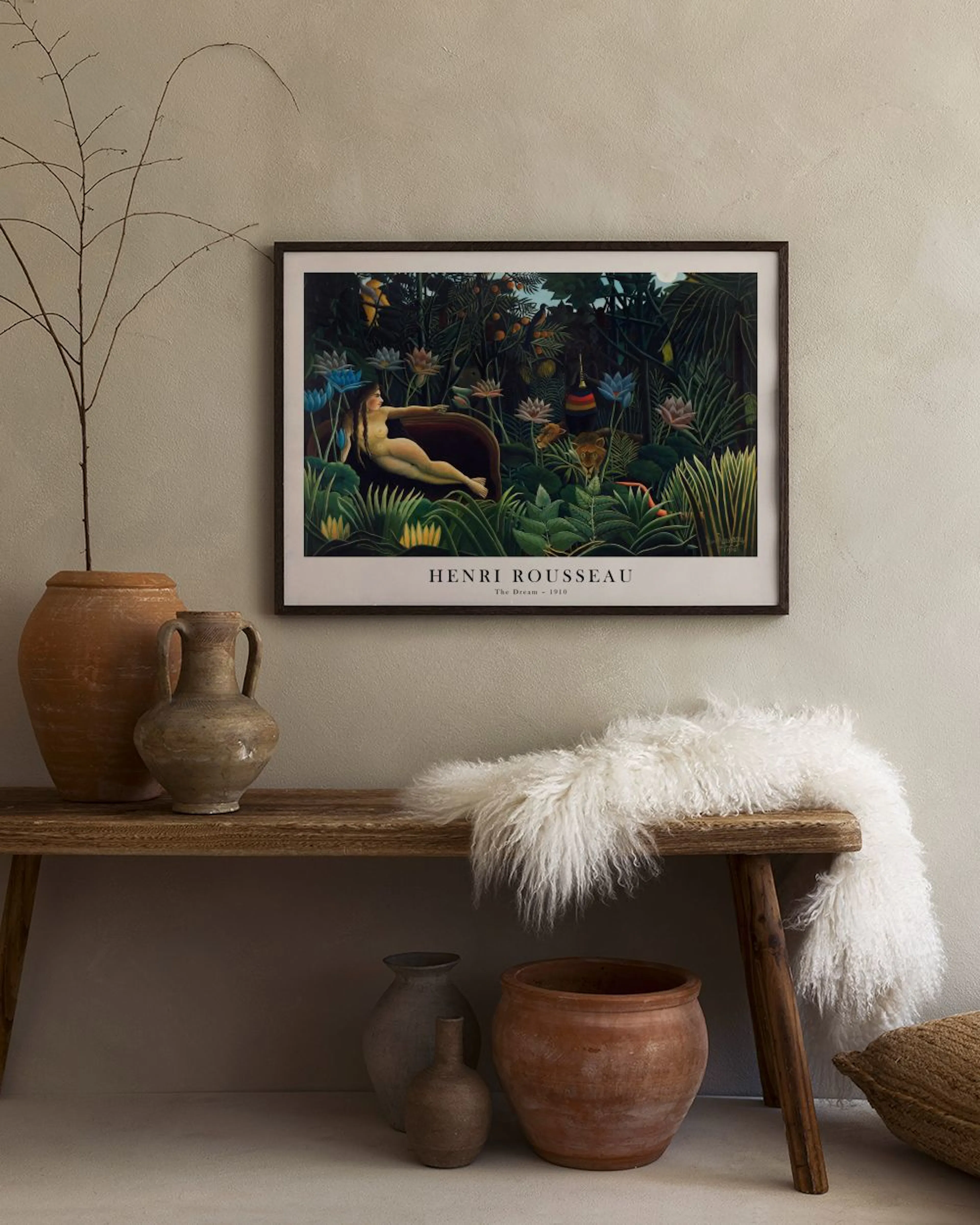 Henri Rousseaus The Dream print with a nude woman in a lush jungle, hanging above a green velvet chair.