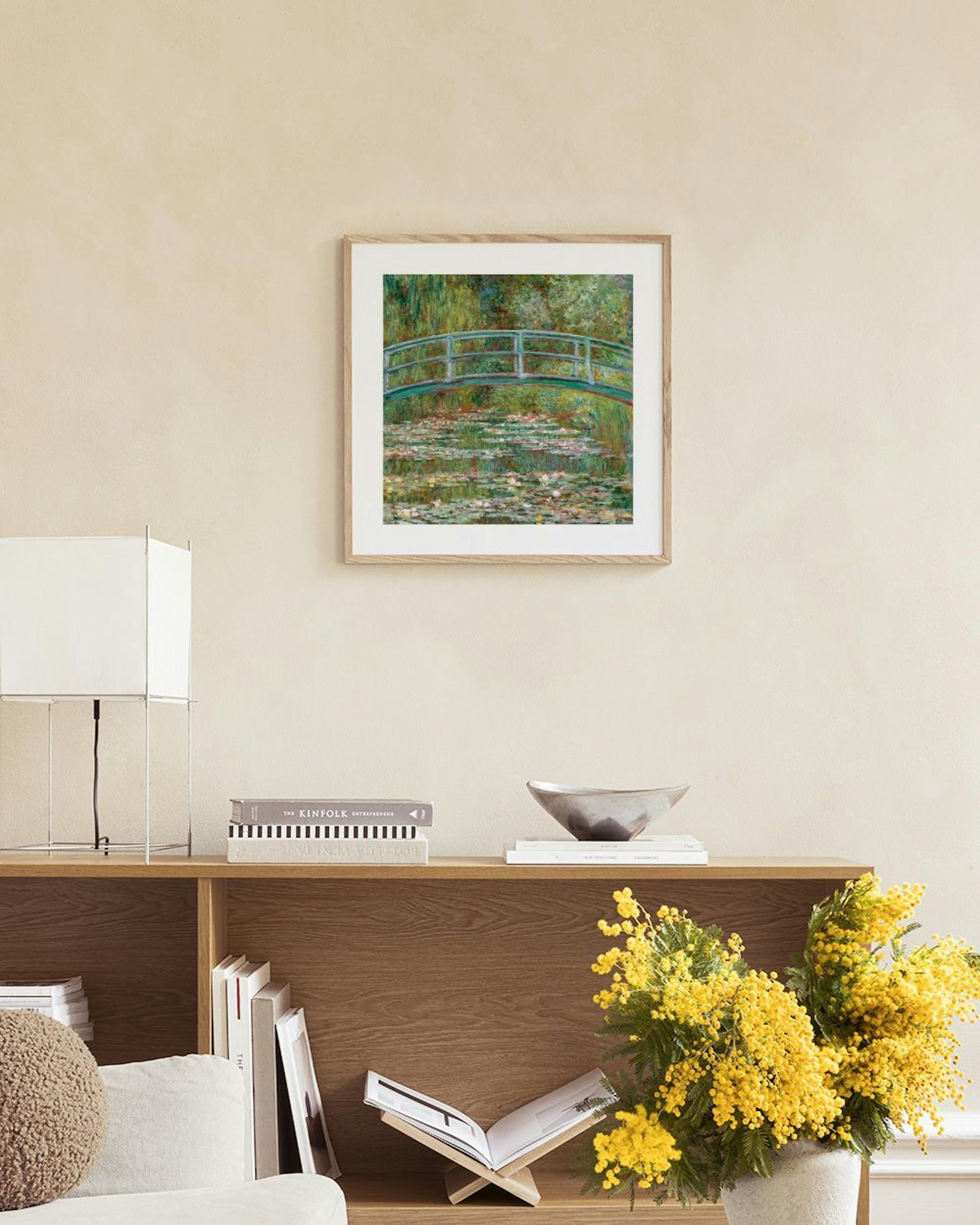 Poster com pintura de Monet da ponte japonesa e nenúfares, pendurado acima de uma secretária de madeira clara com livros e objet