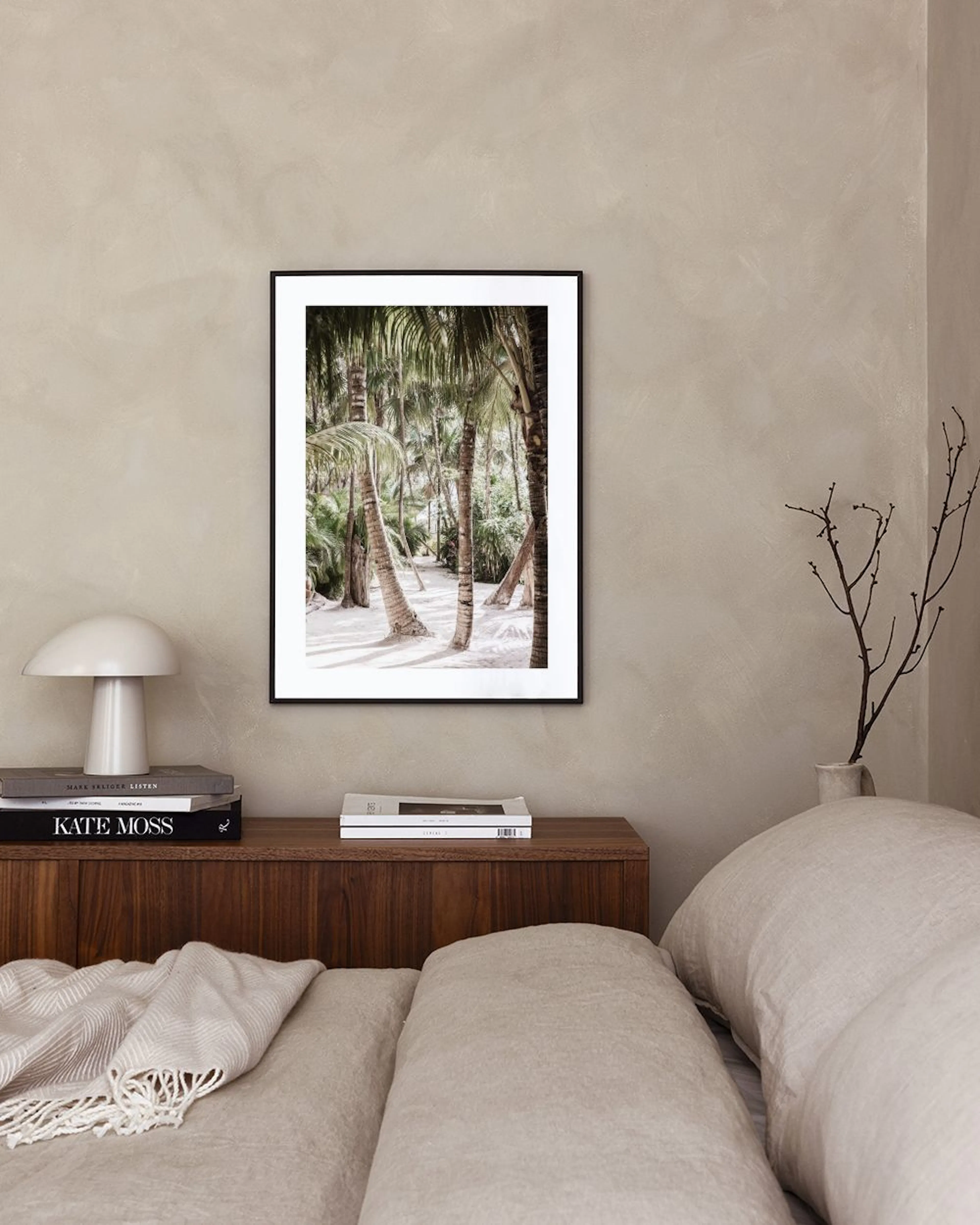 Affiche avec des palmiers et du sable blanc, affichée dans un salon moderne au-dessus dune table basse en bois.