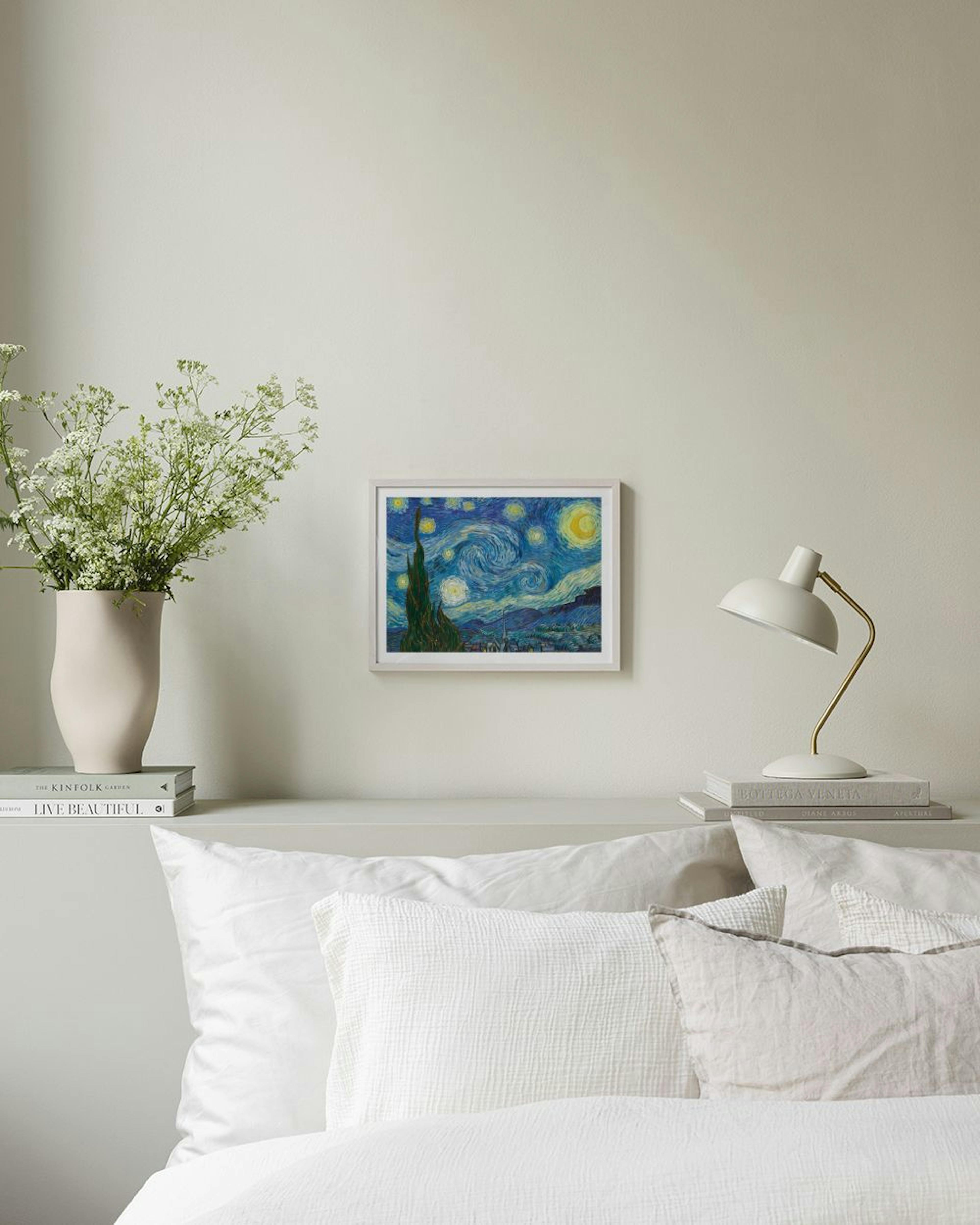 Póster de La Noche Estrellada de Van Gogh colgado en una pared gris, con mesa y sillón al lado.