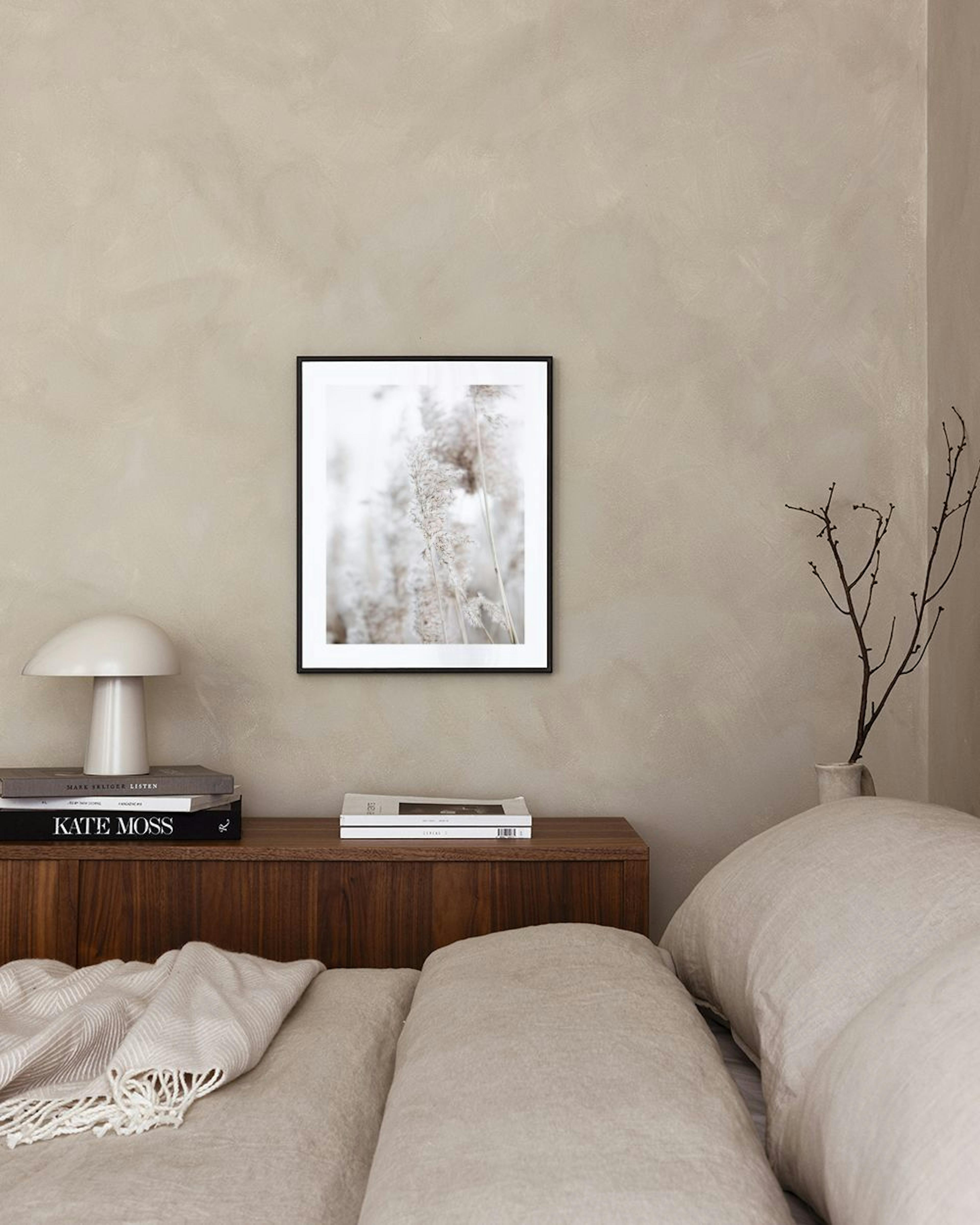 Poster van rietpluimen in zachte, beige tinten, hangend boven een houten bureau in een minimalistische kamer.
