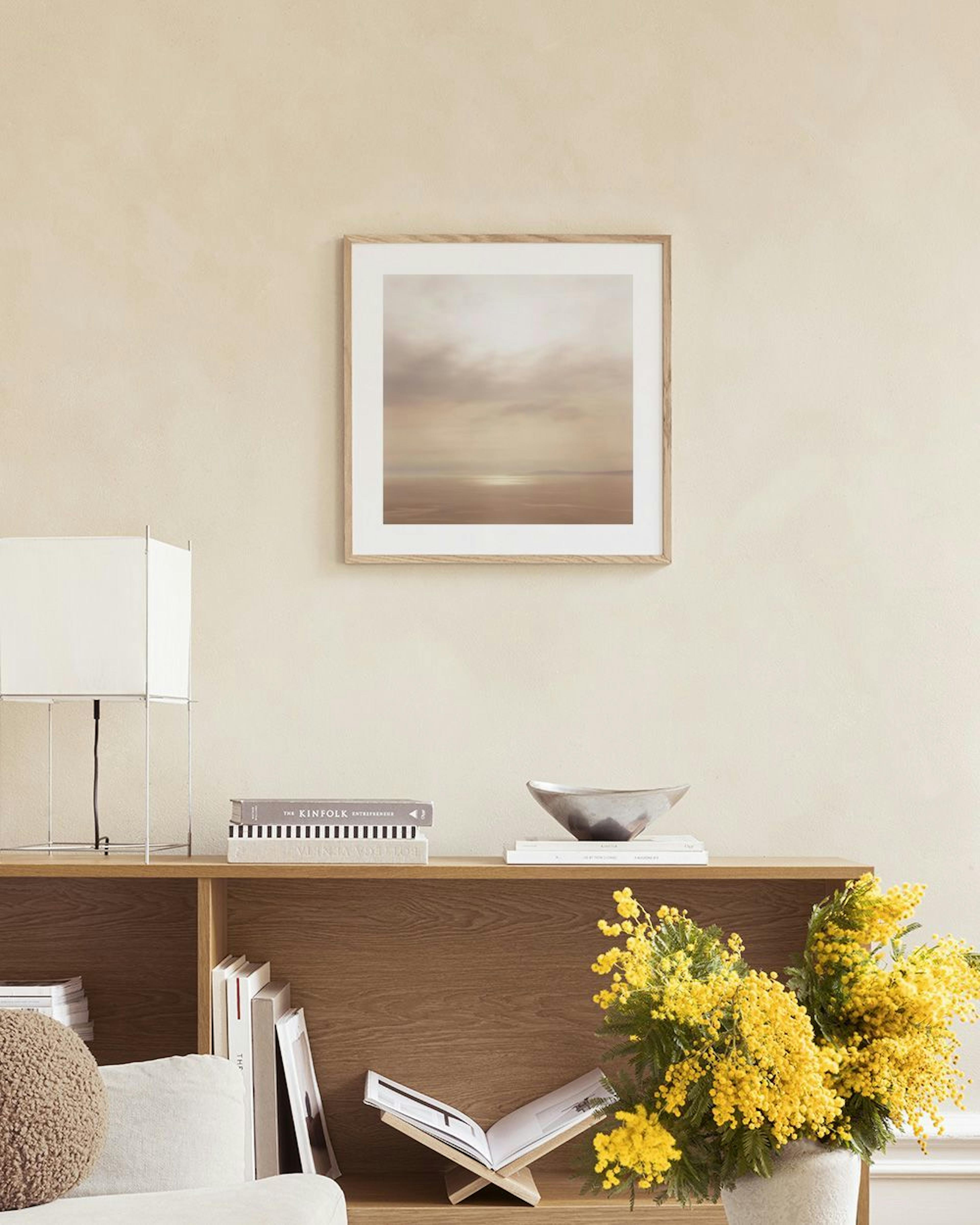 Poster van een zonsondergang op het strand, hangend boven een sidetable met kandelaars en kussens op een bank.