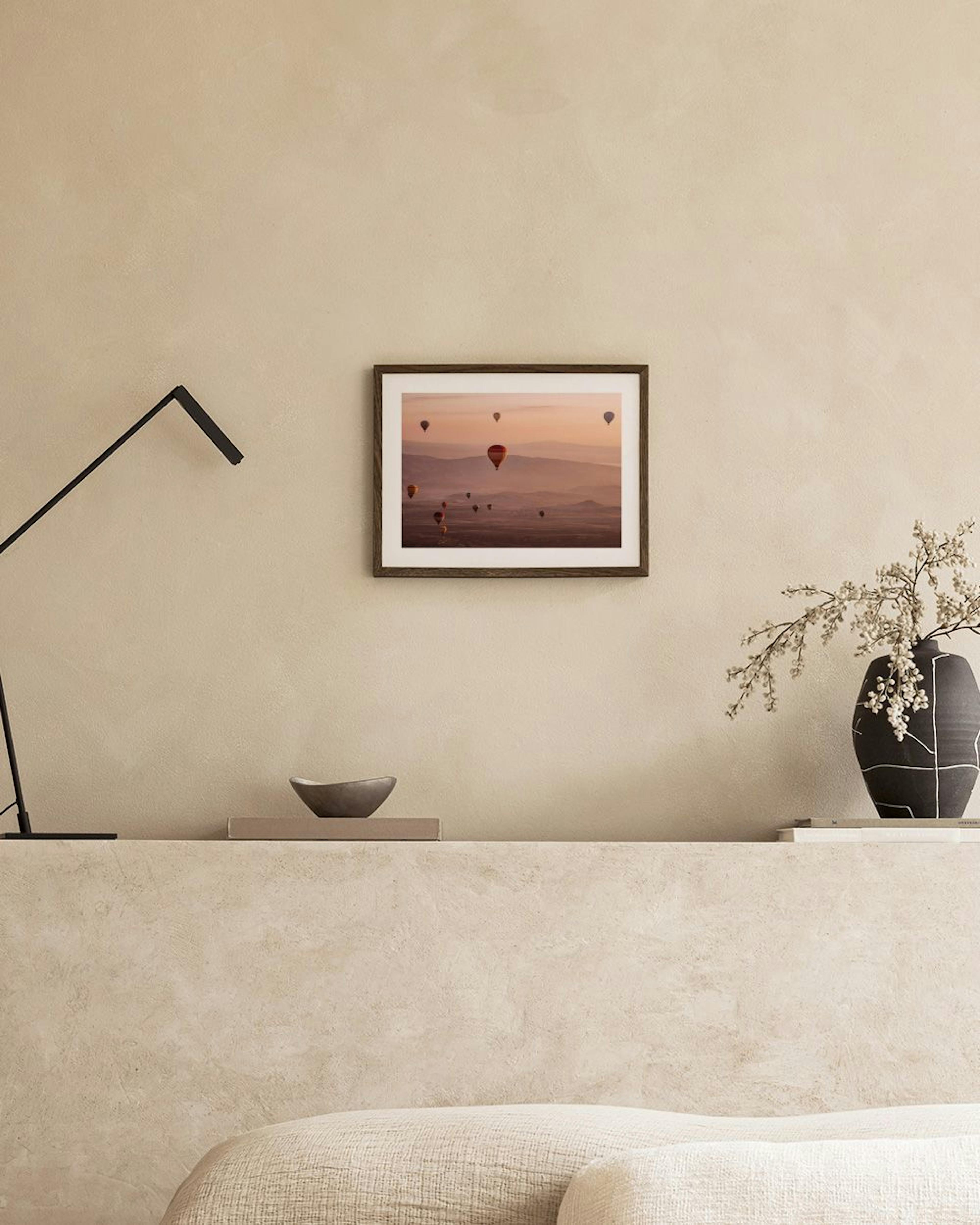 Poster von Heißluftballons über einer hügeligen Landschaft bei Sonnenaufgang, auf einer Bank mit Vase und Büchern.