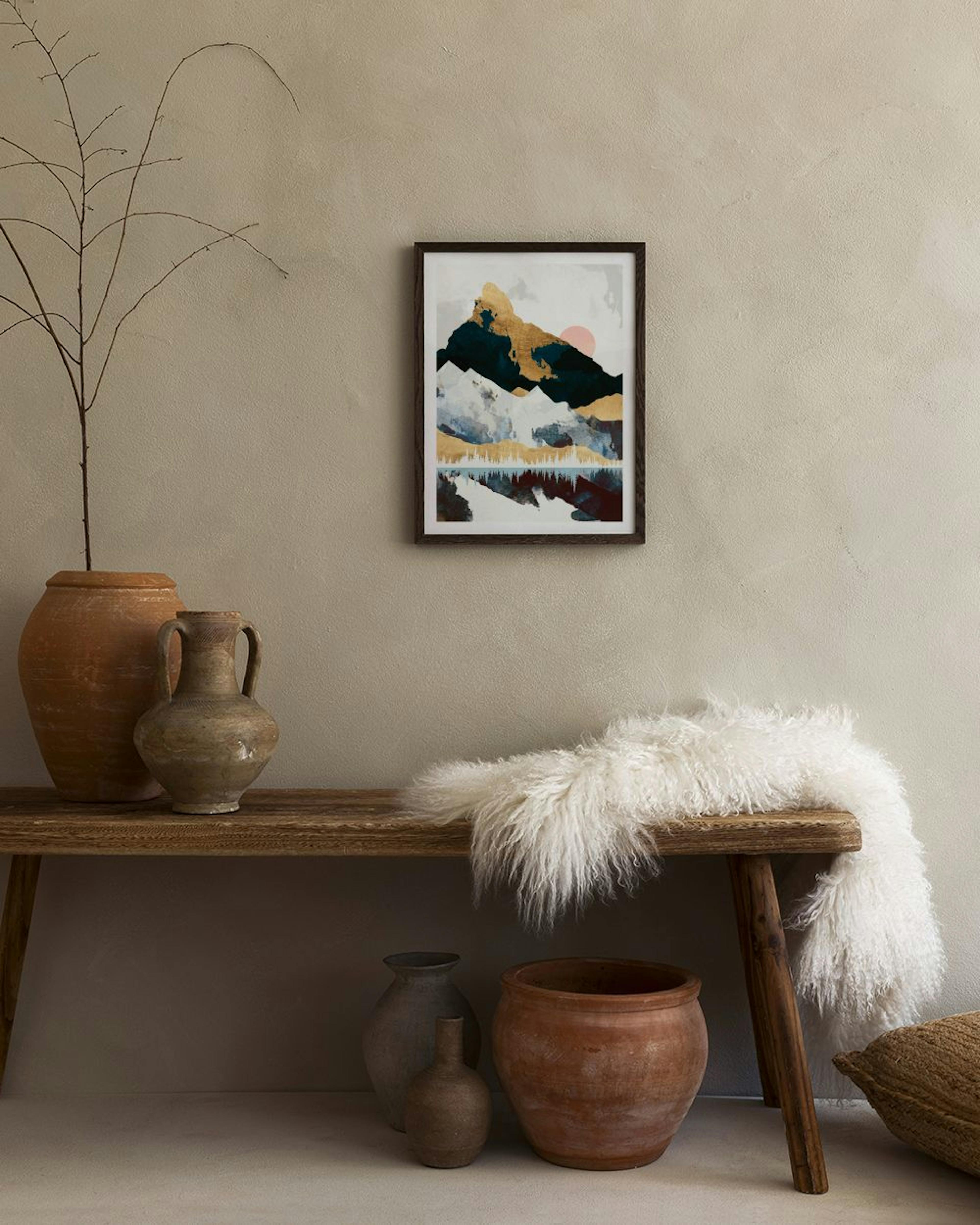 Abstract mountain print with black, white, and gold peaks reflecting on water, displayed in a modern living room.