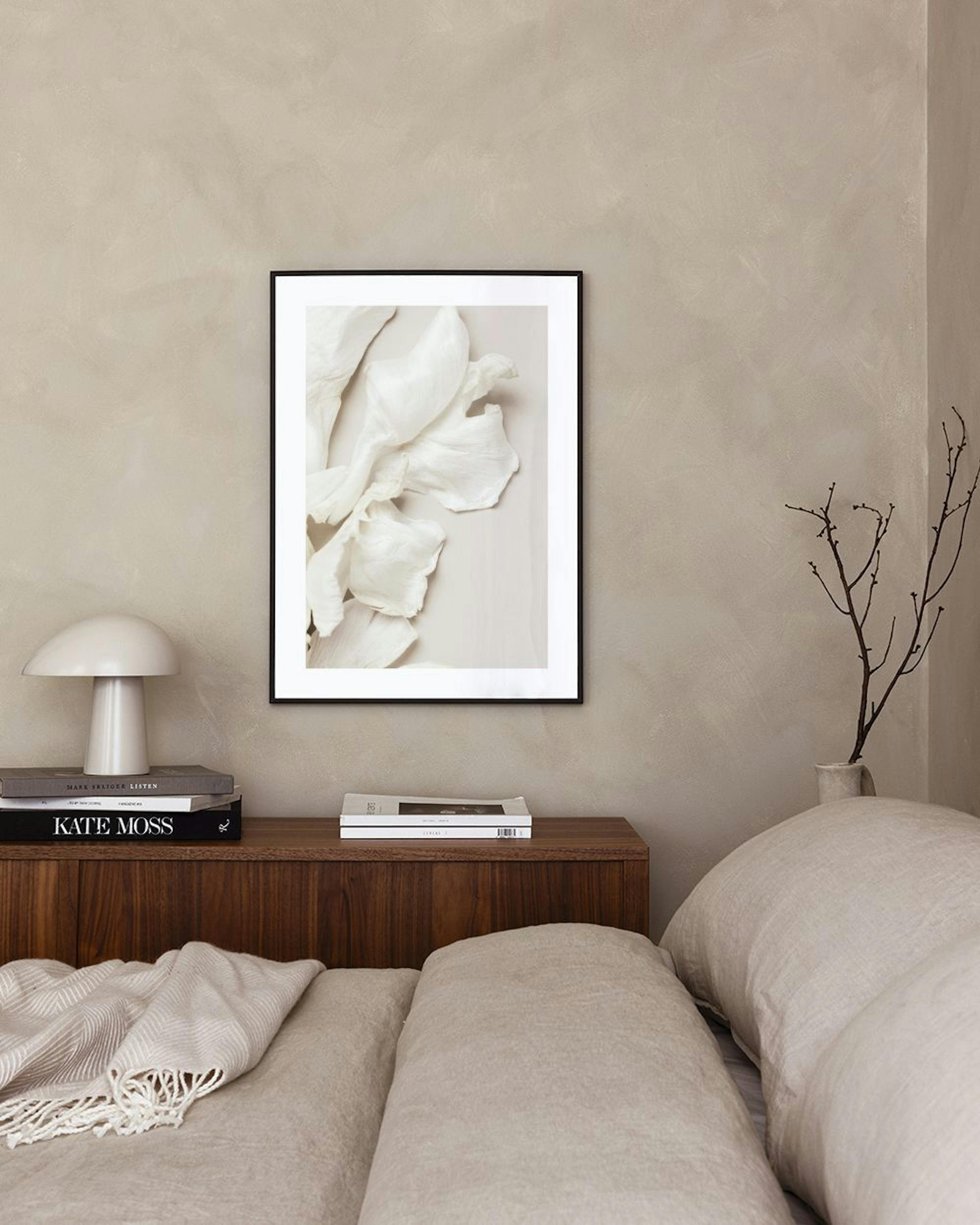 Poster met gebroken witte, abstracte bloemblaadjes op een lichte achtergrond, hangend boven een blauwgroene fauteuil.