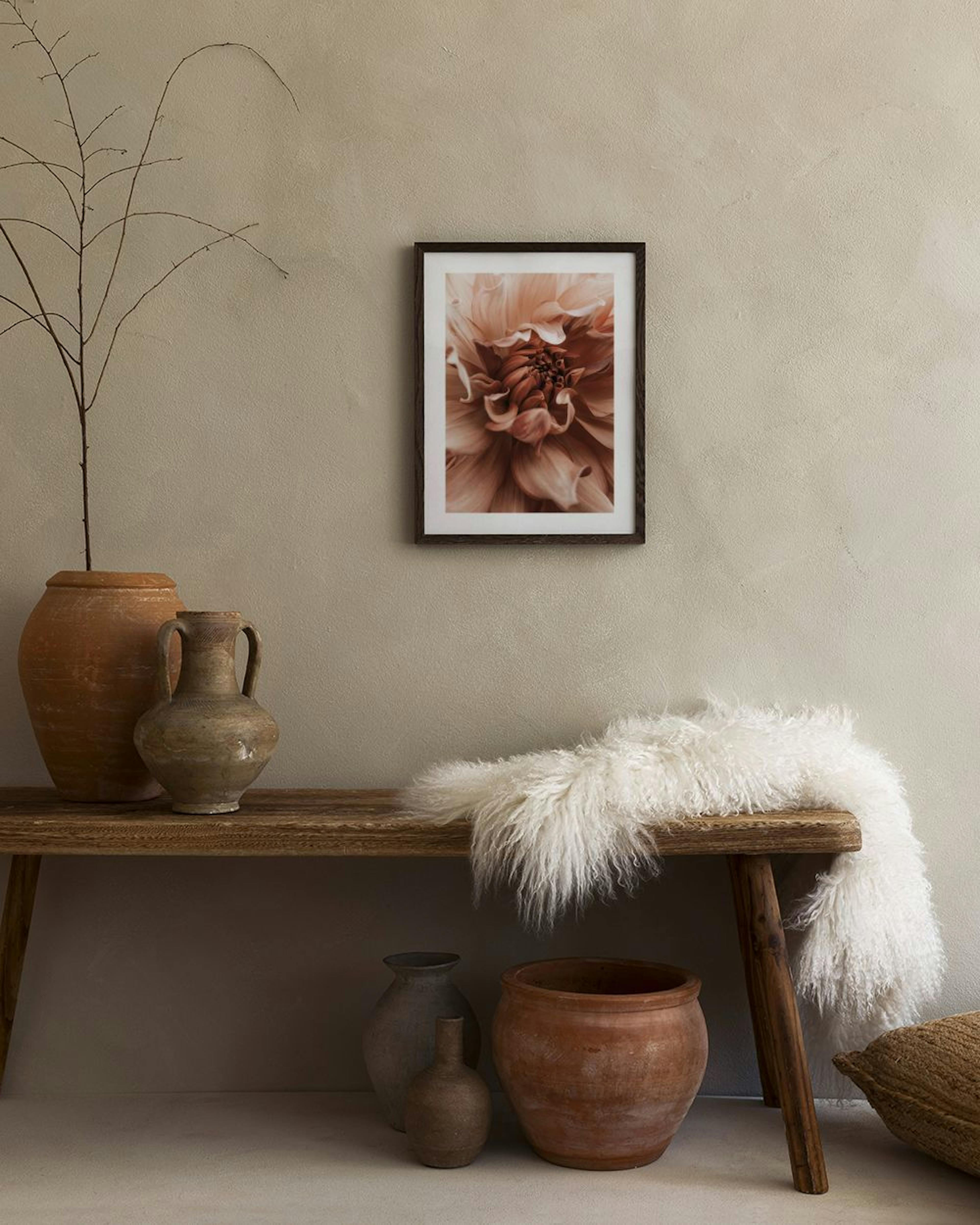 Poster de uma dália em tons de castanho e bege, pendurado em parede rosa sobre um carrinho de bar dourado e uma cadeira preta.