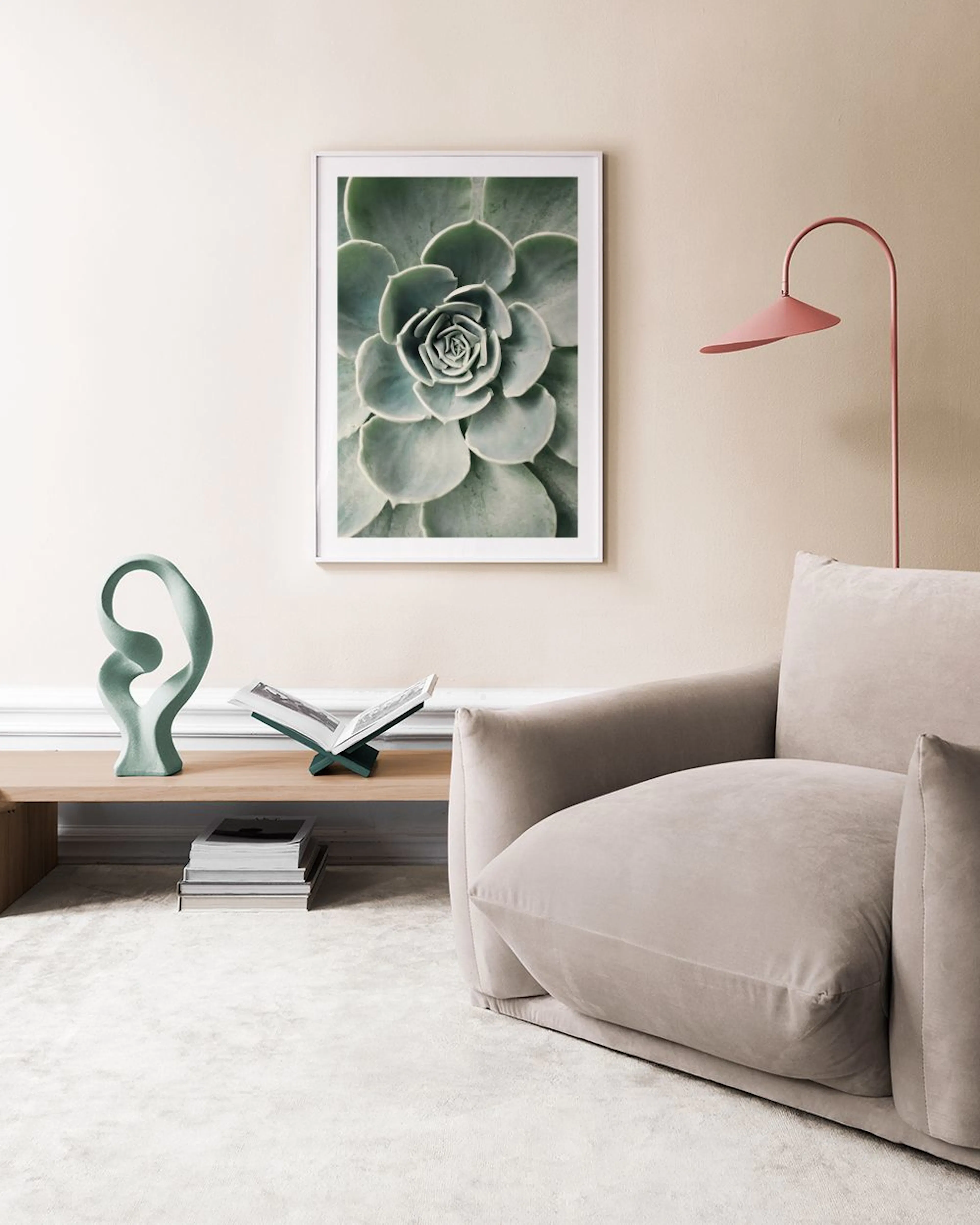 A succulent print hanging above a wooden bench with three ceramic cacti on a green wall.
