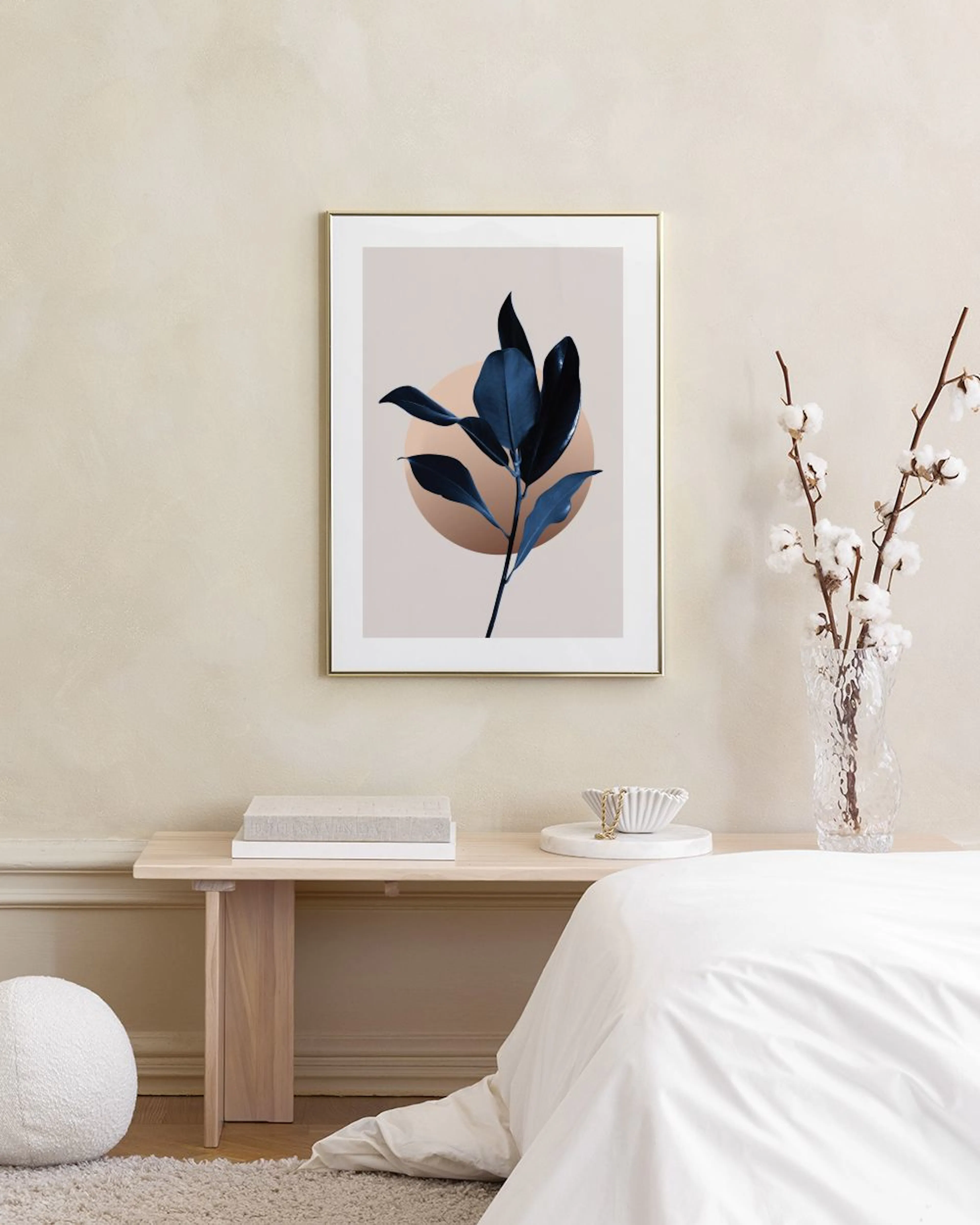A poster of dark blue leaves on a light background with a brown circle, displayed in a living room above a wooden table.